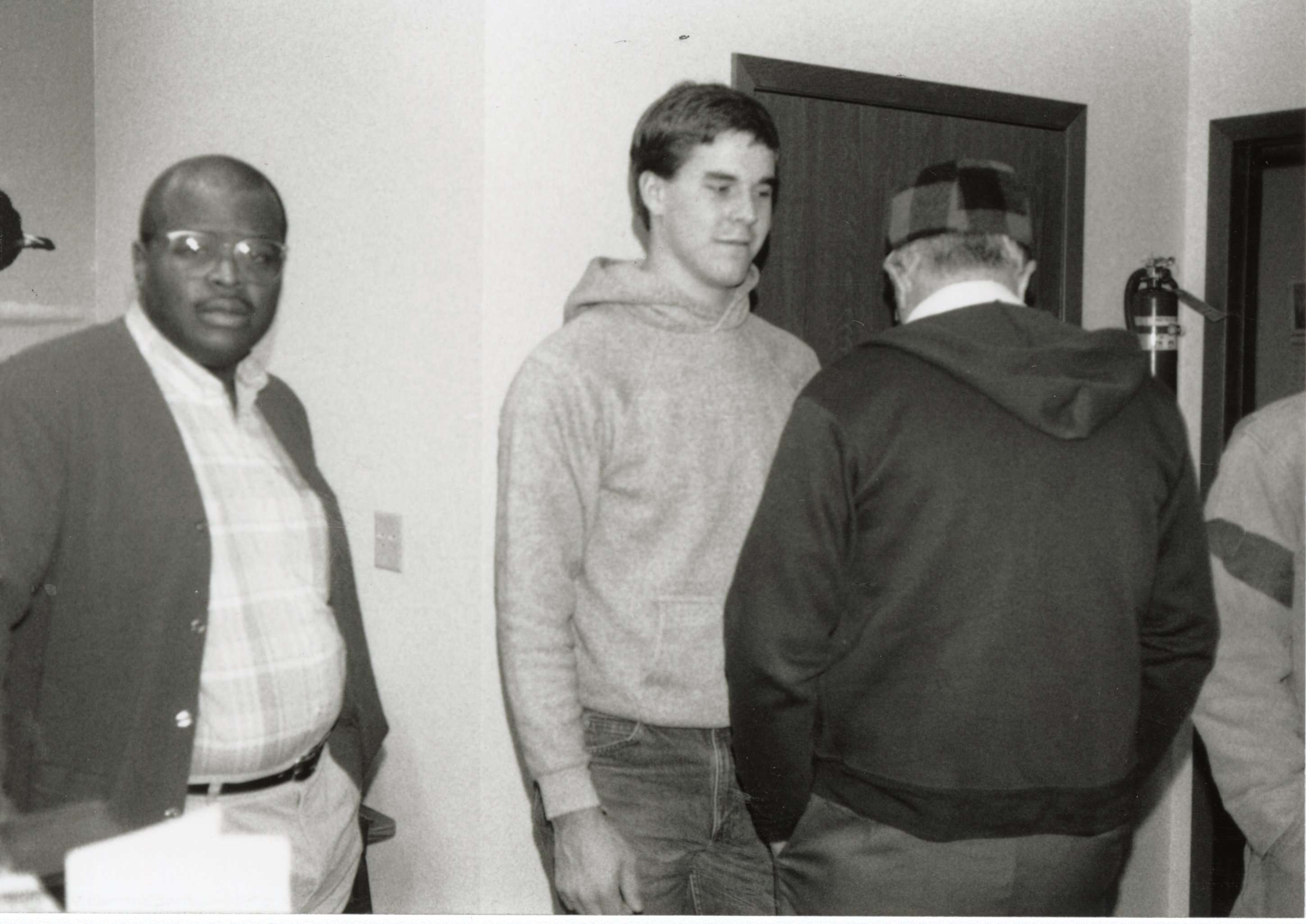 Terry Cosby and John Fruehling stand in a hallway with a man whose back faces the camera.