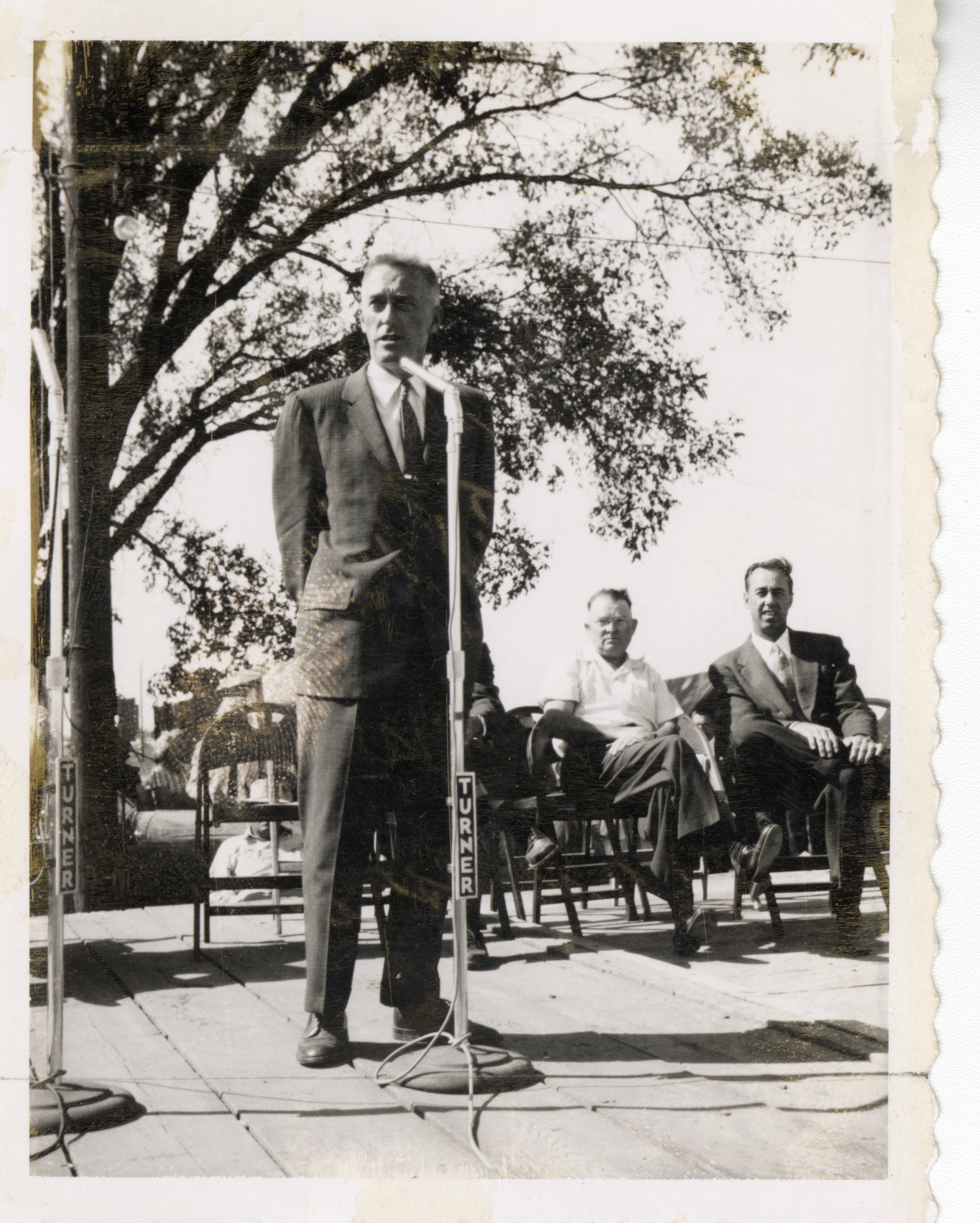 Man in Suit Talks into Microphone