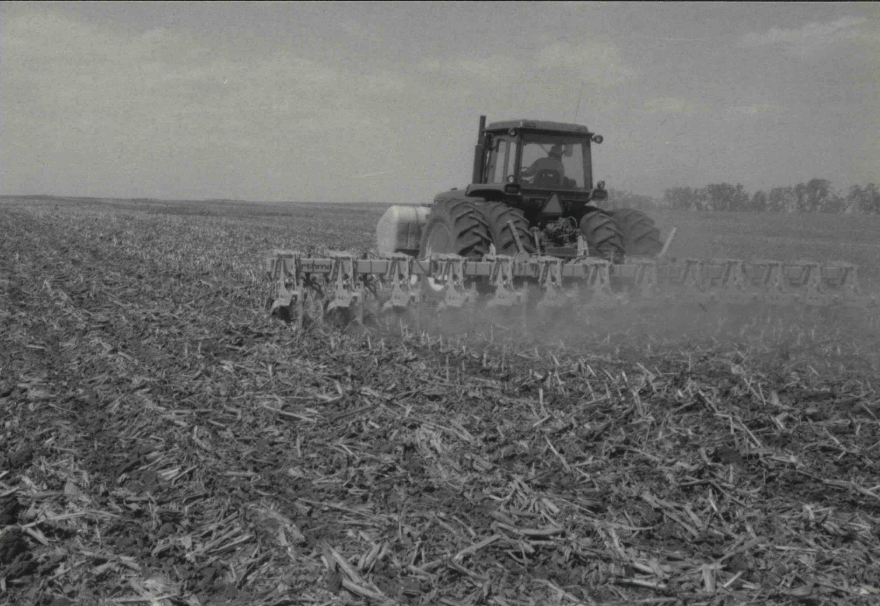 Tractor pulling disk in cornfield<br />
