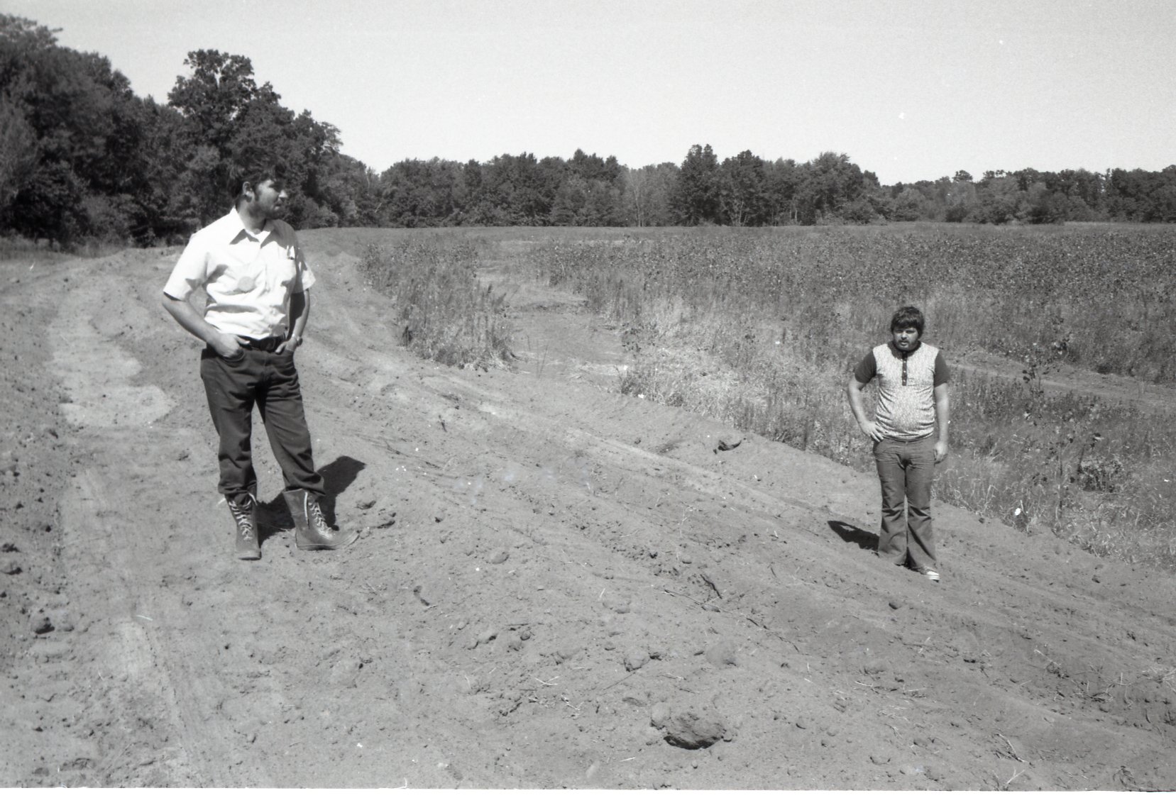 Two men stand in dusty road