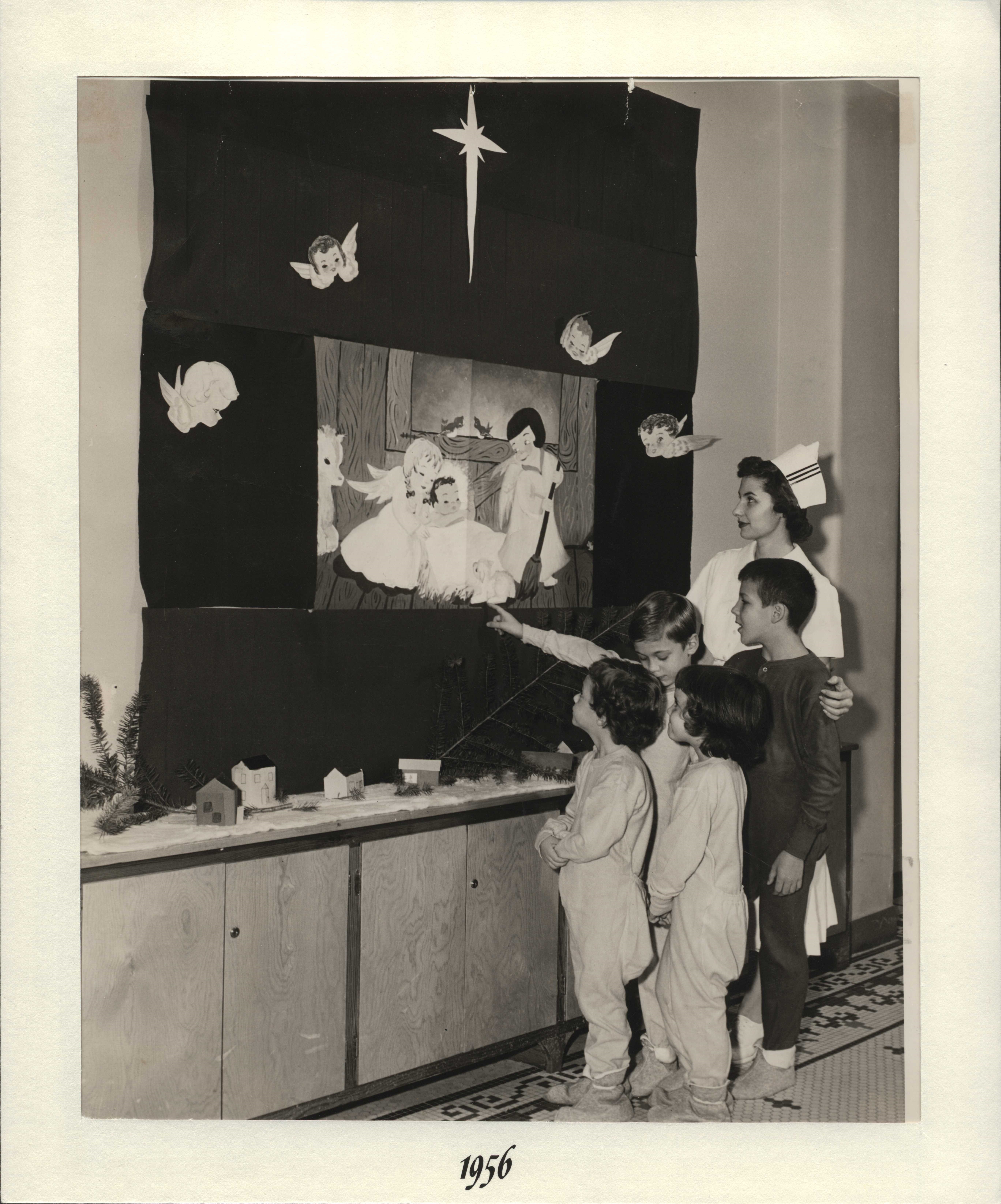 Nurse with children at nativity scene.