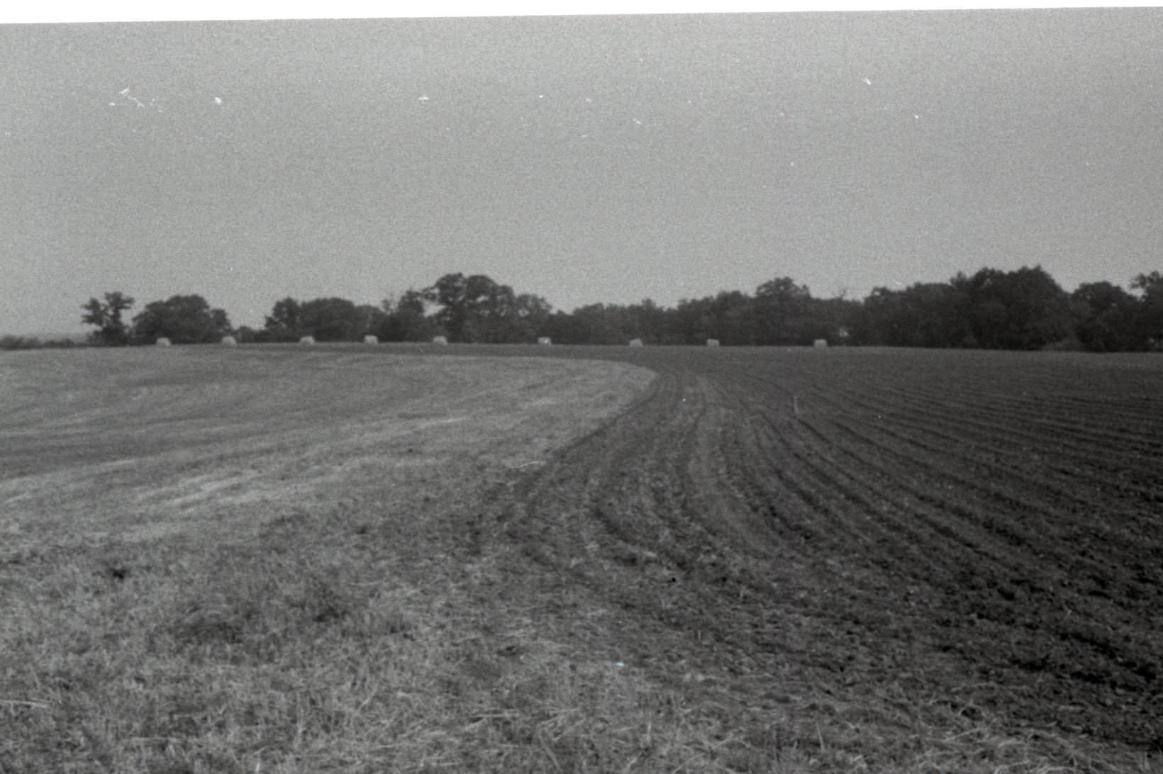 Plowed Farmland with Hay Bales in Back