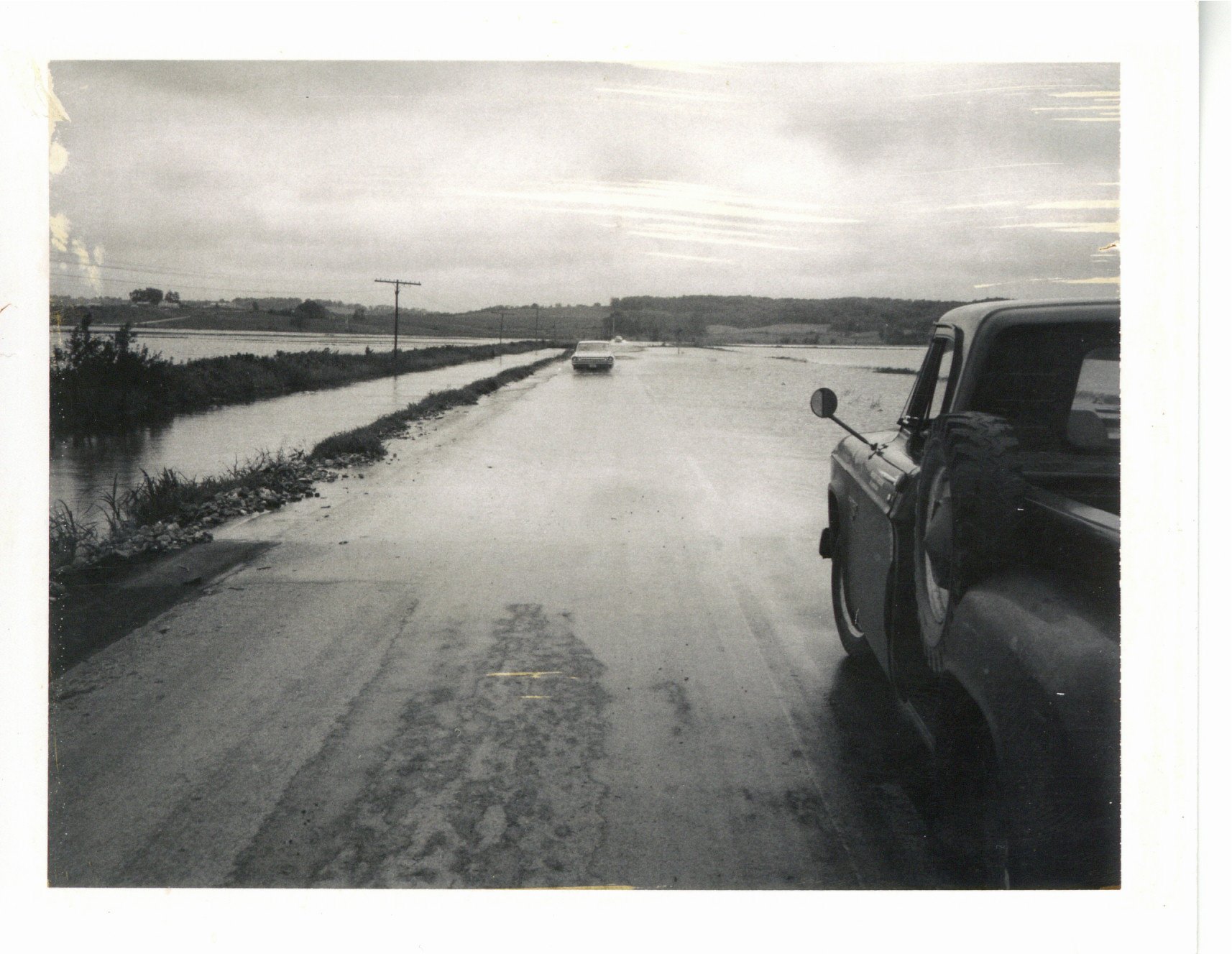Water running across road in Tama Co., 1969