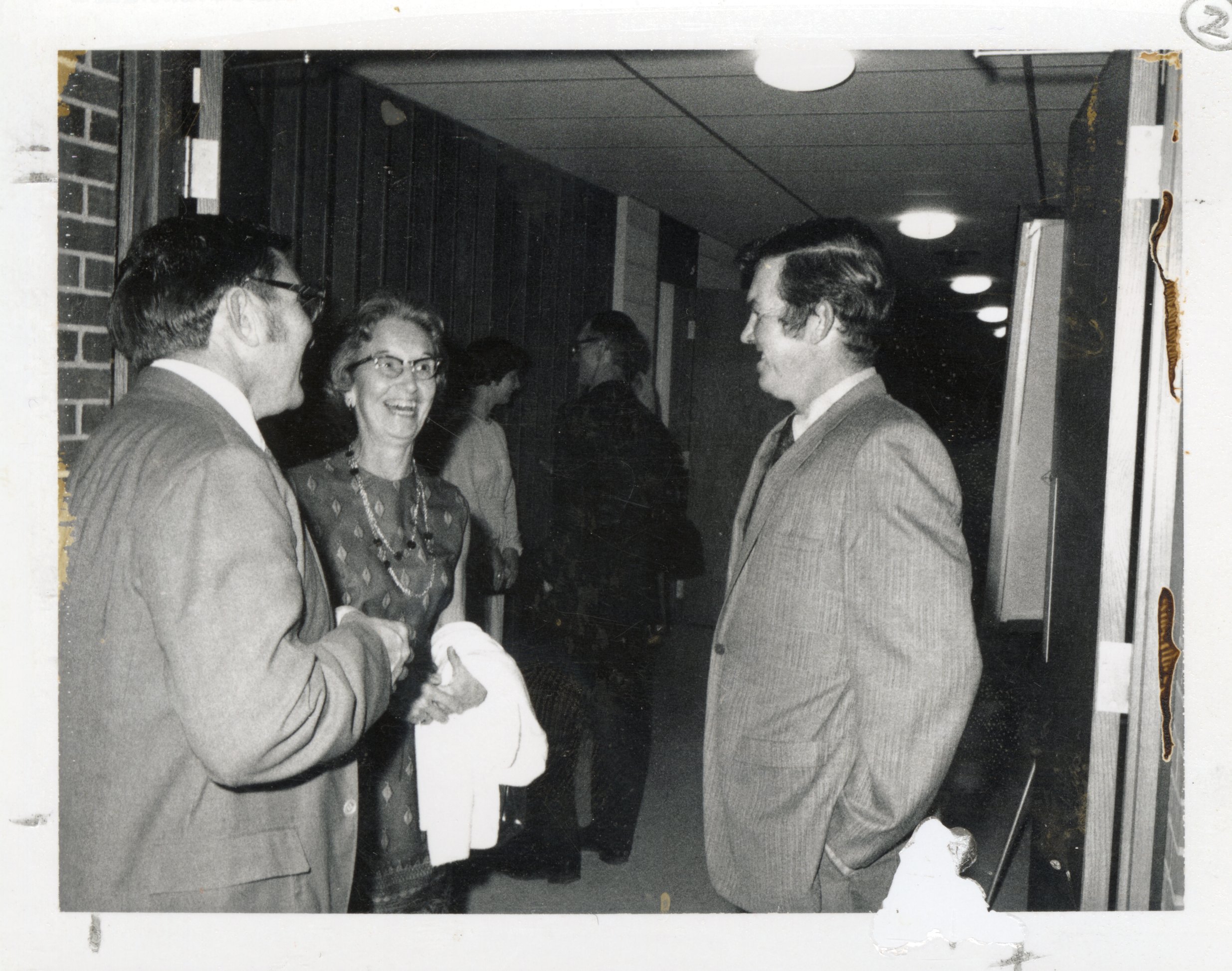 1970s  Two men and a woman talk in hallway