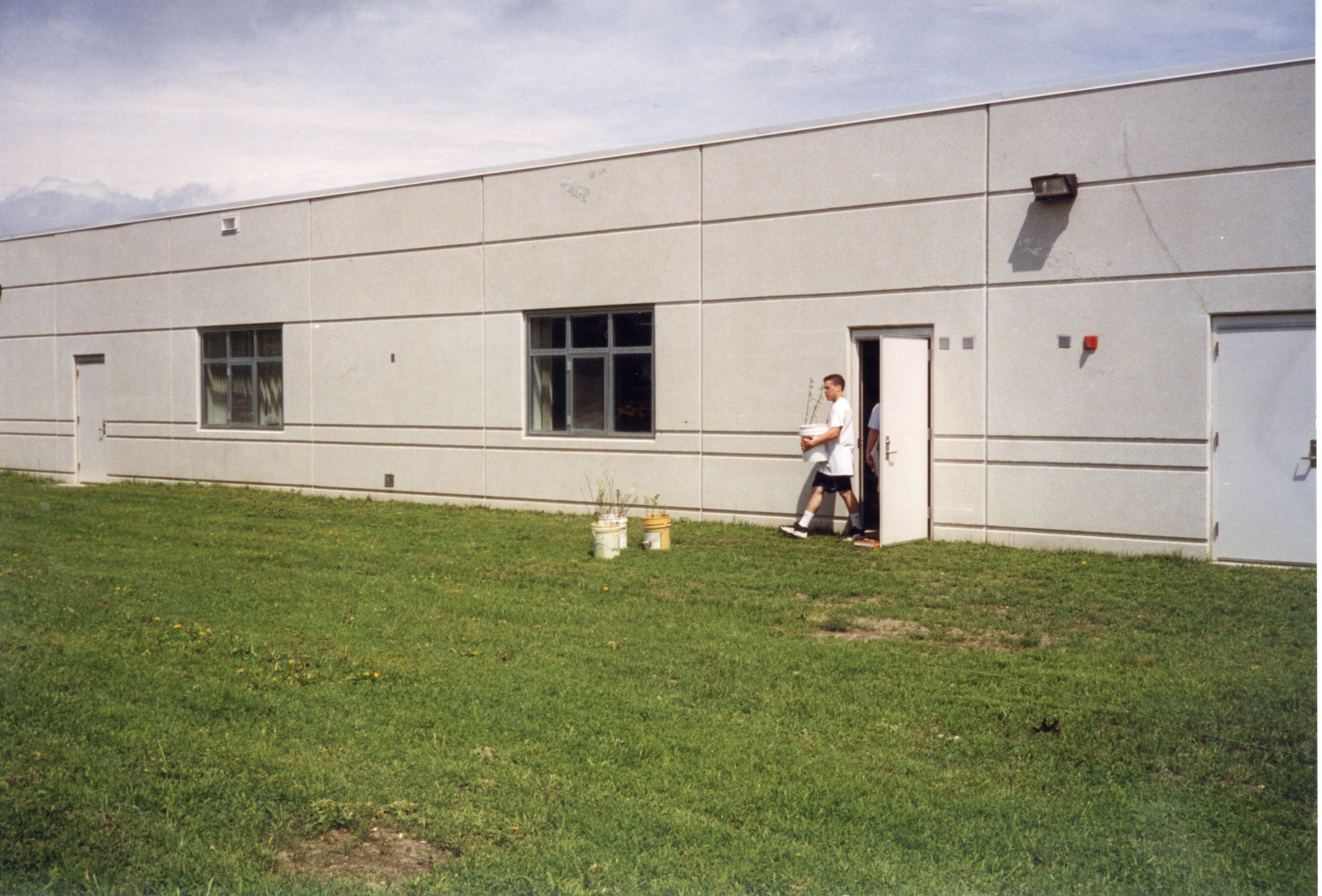1999 Student brings a tree in a bucket out of West Burlington High School to be planted with other trees sitting in buckets