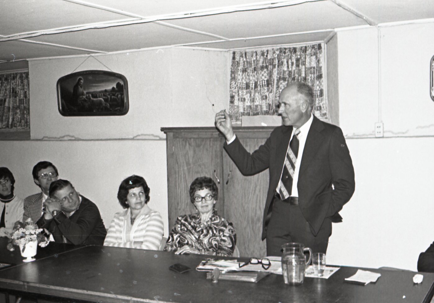Standing man speaks to group at meeting