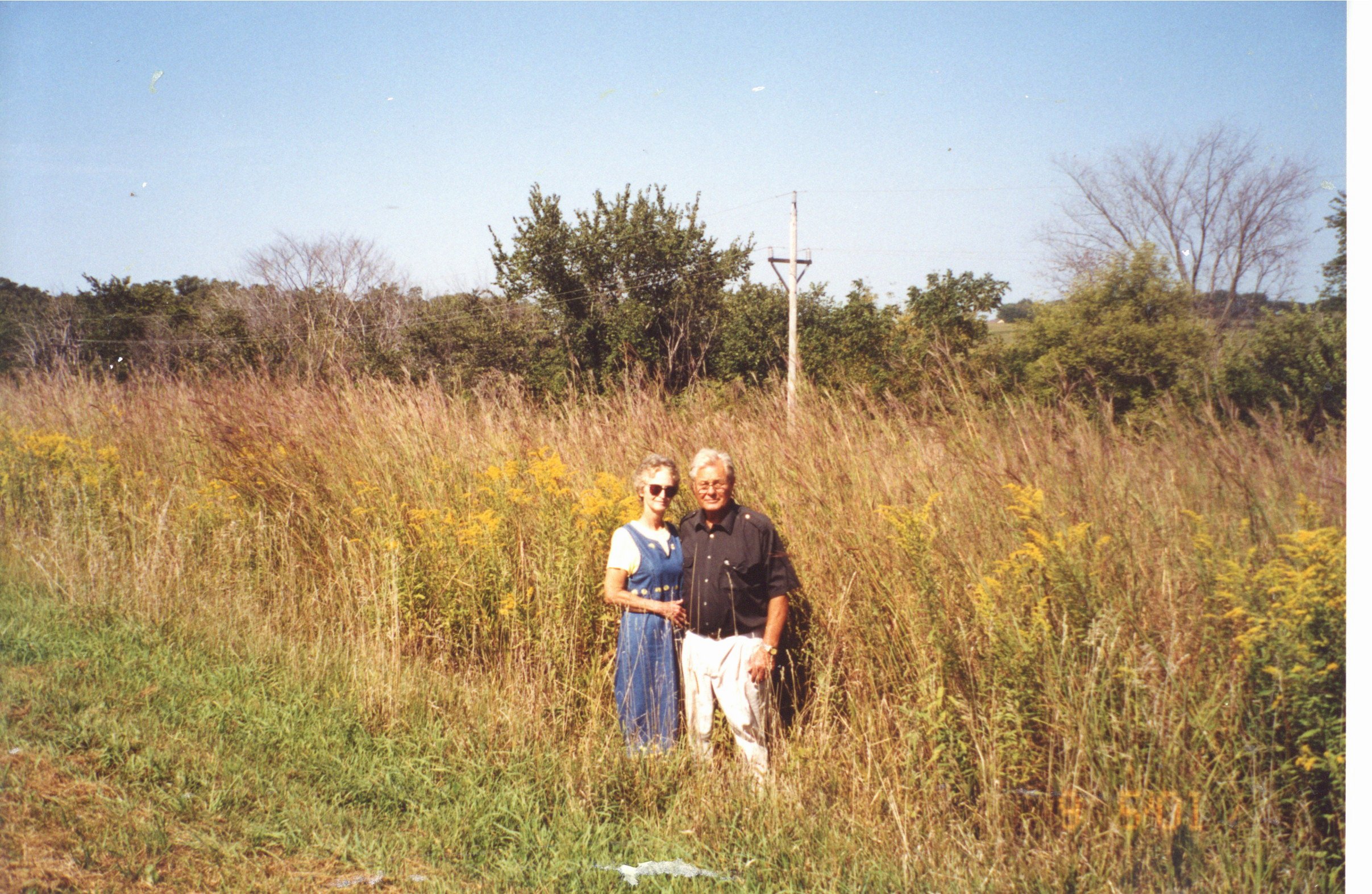 Man and woman standing near Big Bluestem and Golden Rod