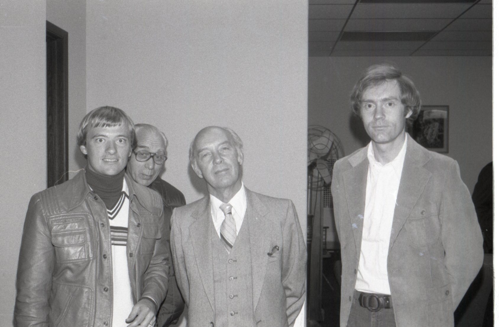 1980 Four men pose for picture at a meeting
