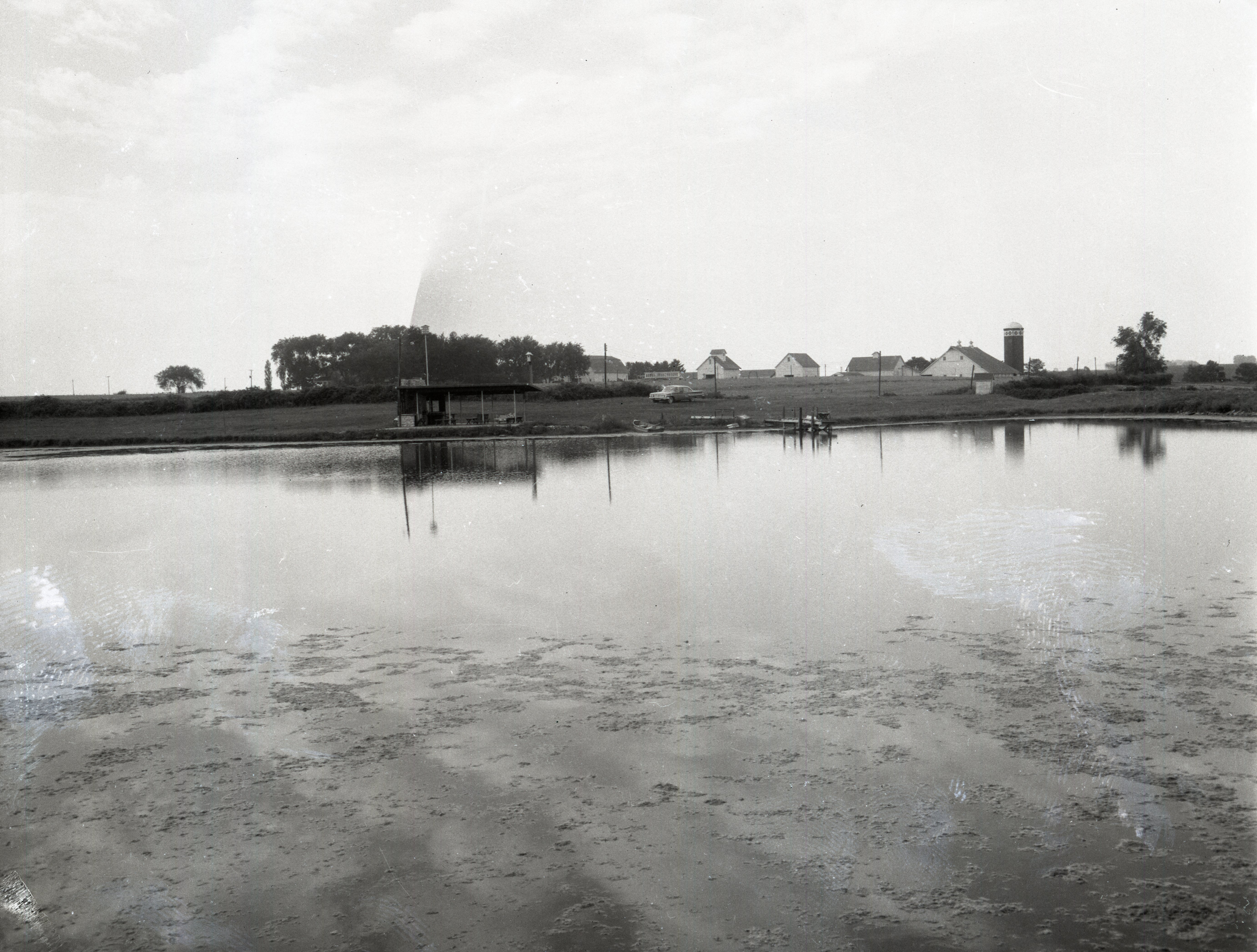 Large pond  with farm buildings on the other side