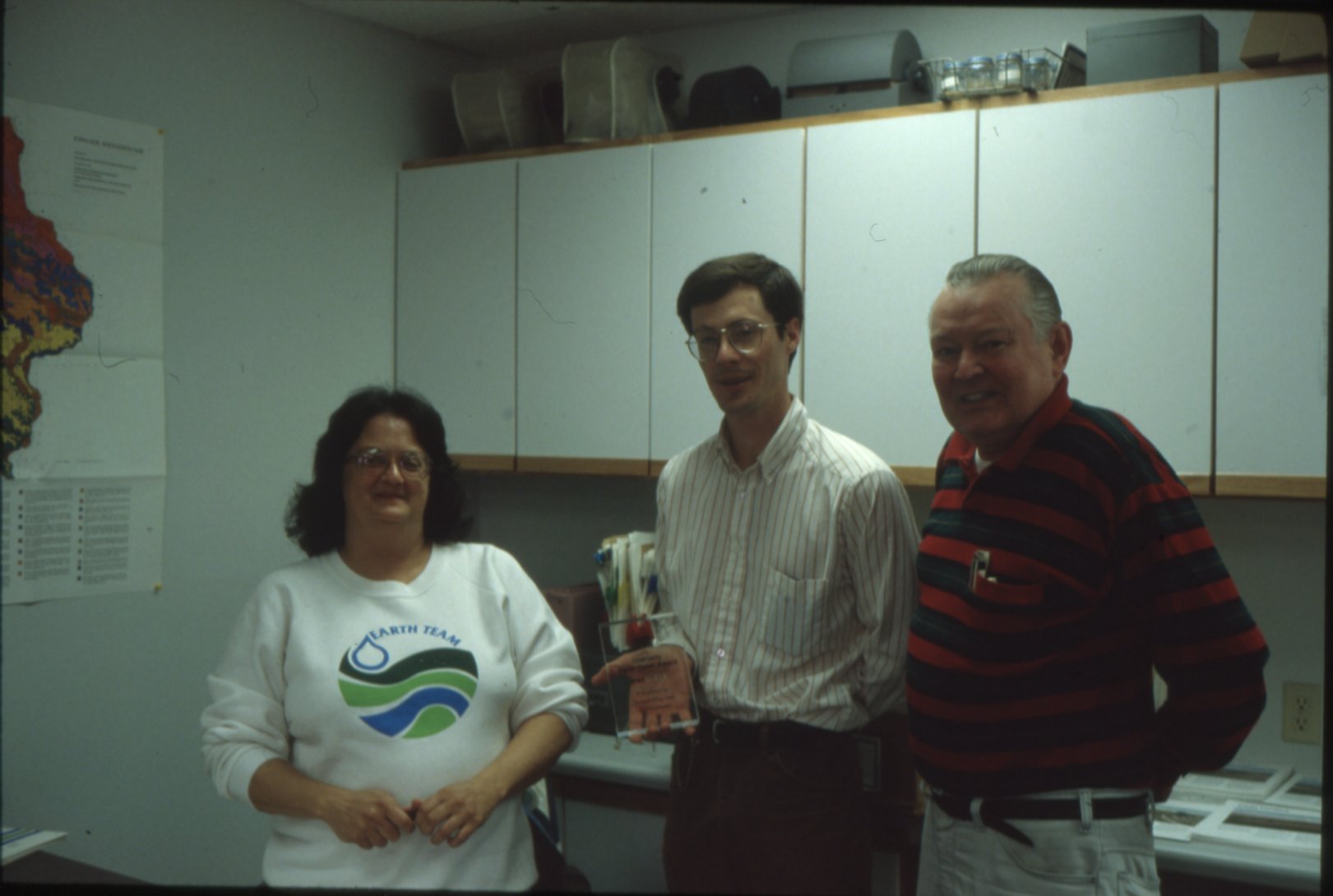 Three unidentified people pose with award