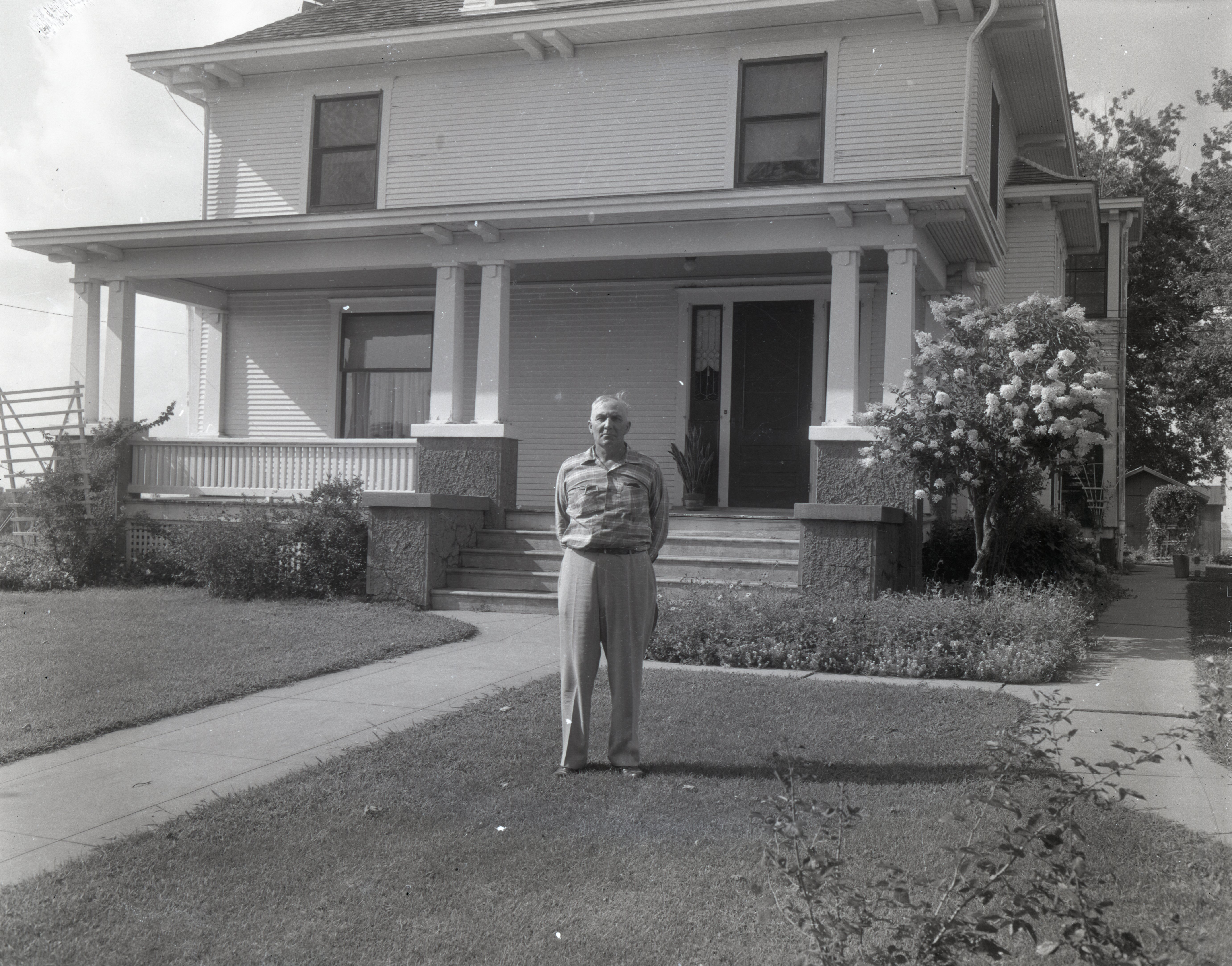 Man stands in front of two story house