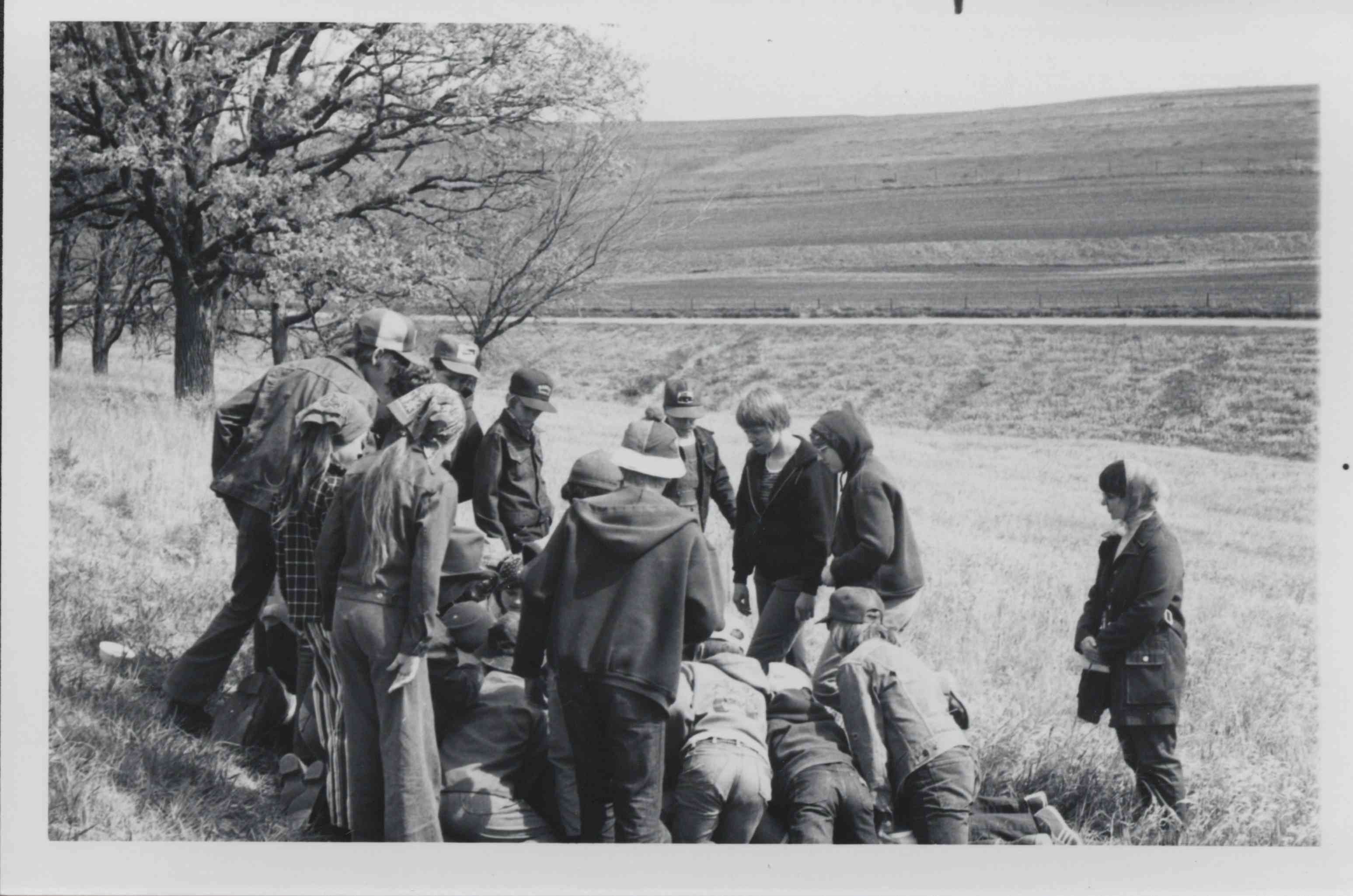 Group kneeling and standing looking at something in middle