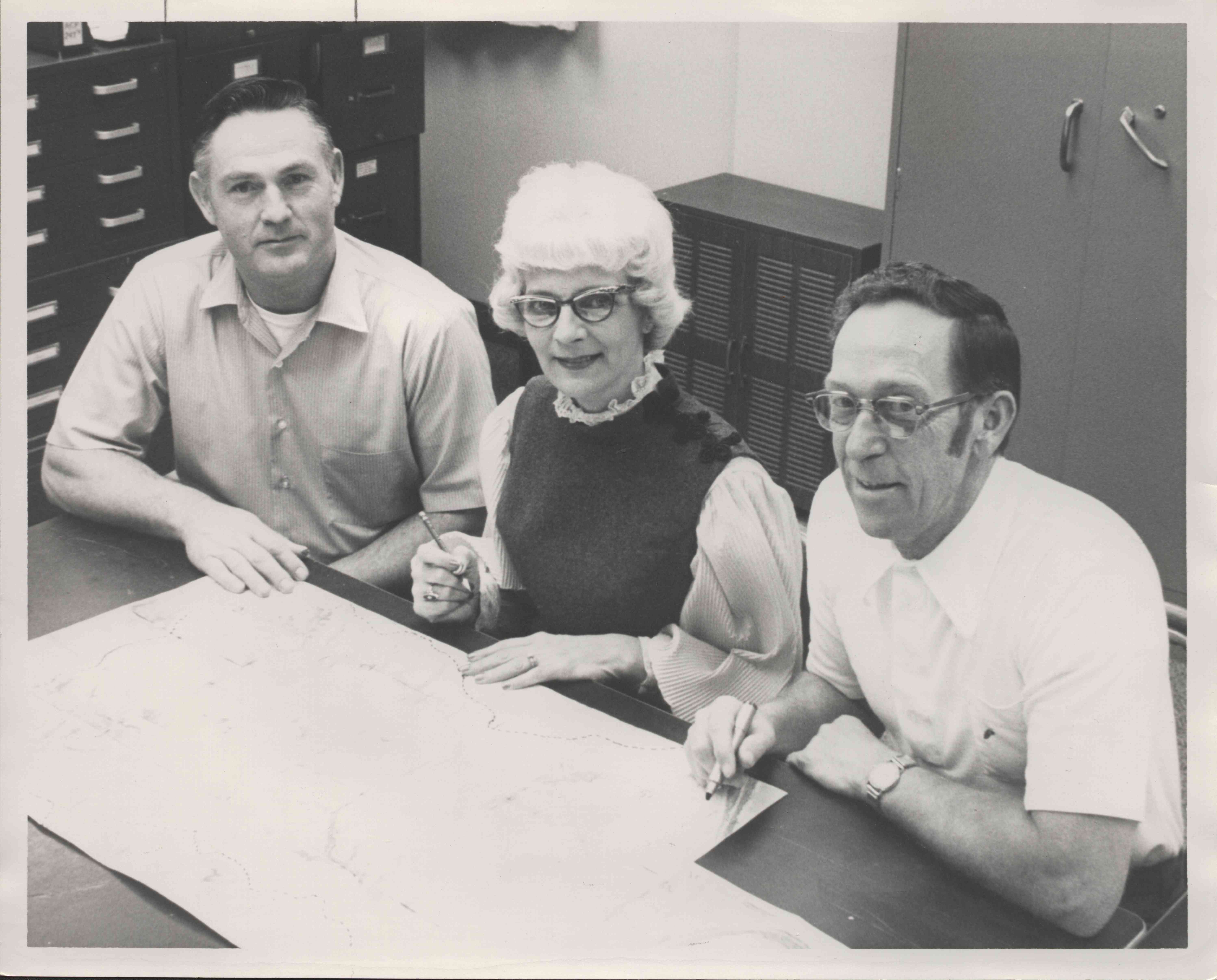 Two Seated Men and a Woman Looking at Map