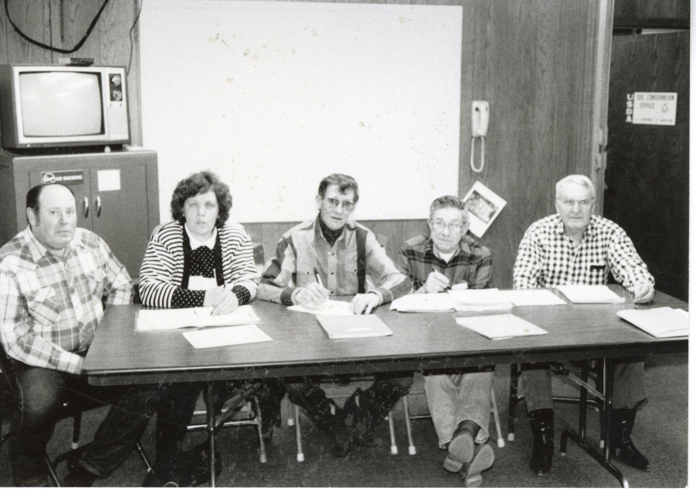 Five unidentified workers sit at table for meeting