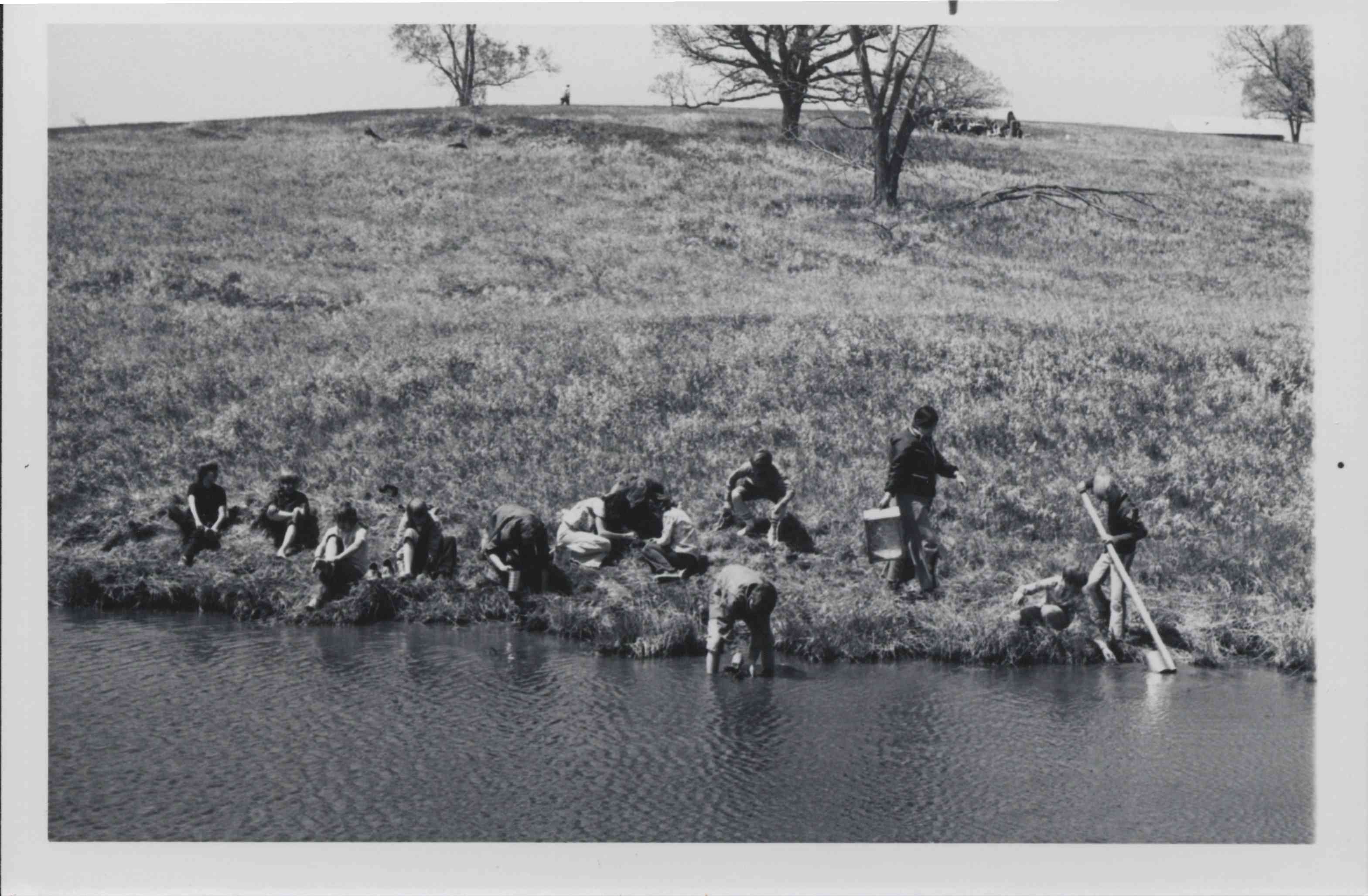 Group Sitting and Standing by Pond