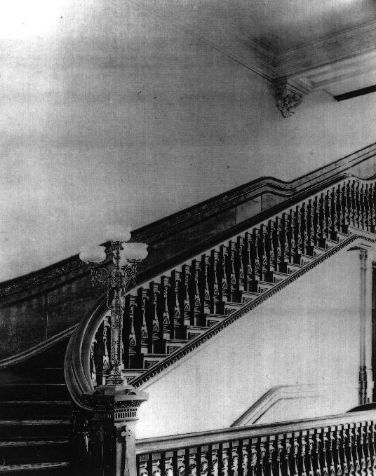 Newel post with gas lamps at the foot of staircases leading to second floor, located at the end of both north and south hallways, circa 1885.