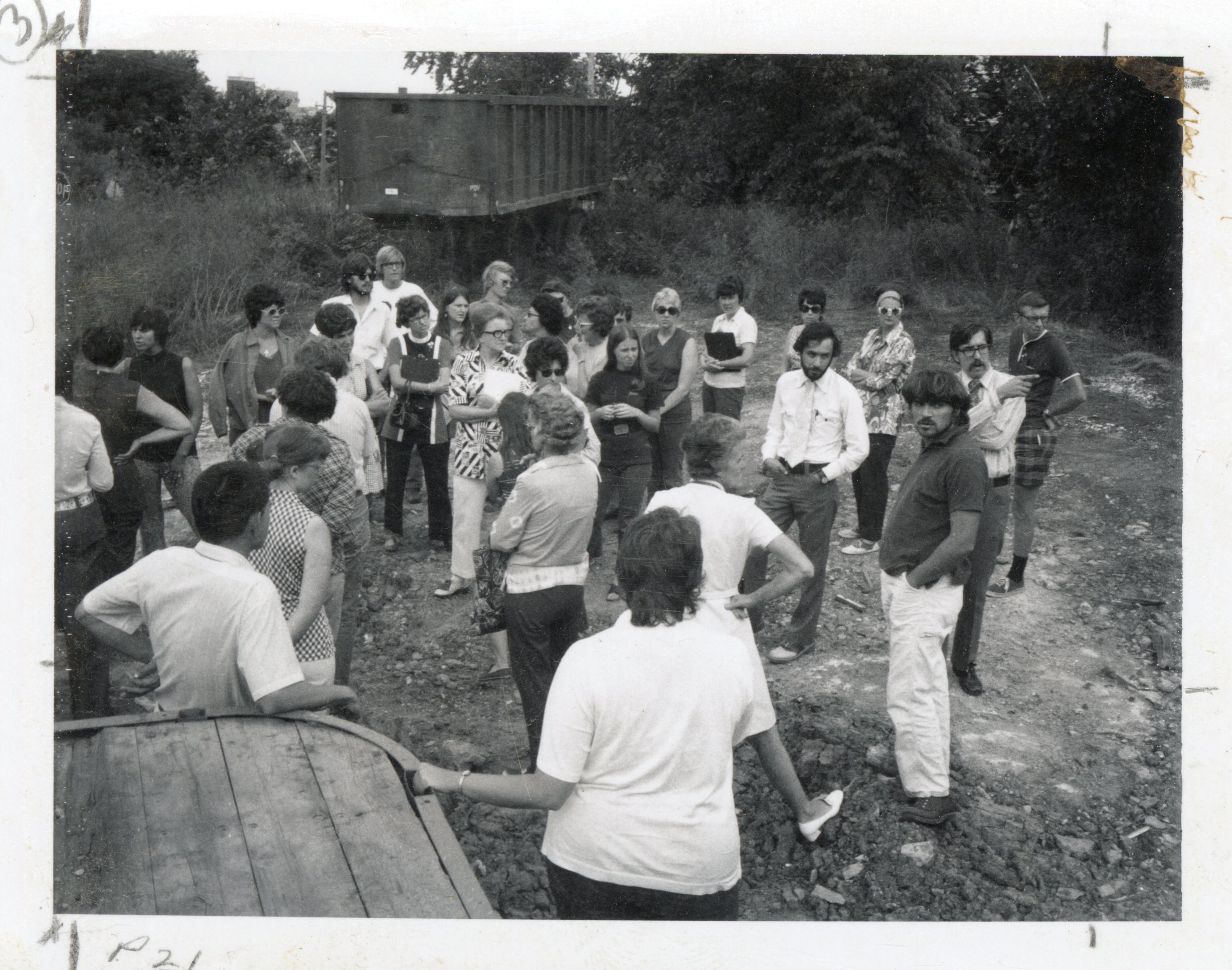 1970s Group stands in field by railroad car