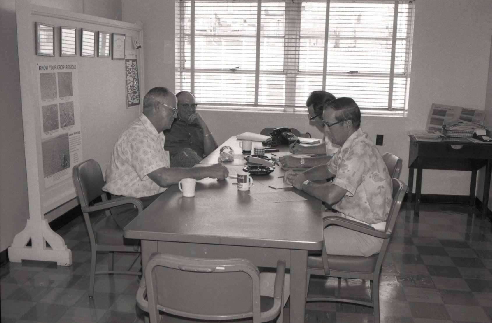 Four men sit at a table at an office meeting