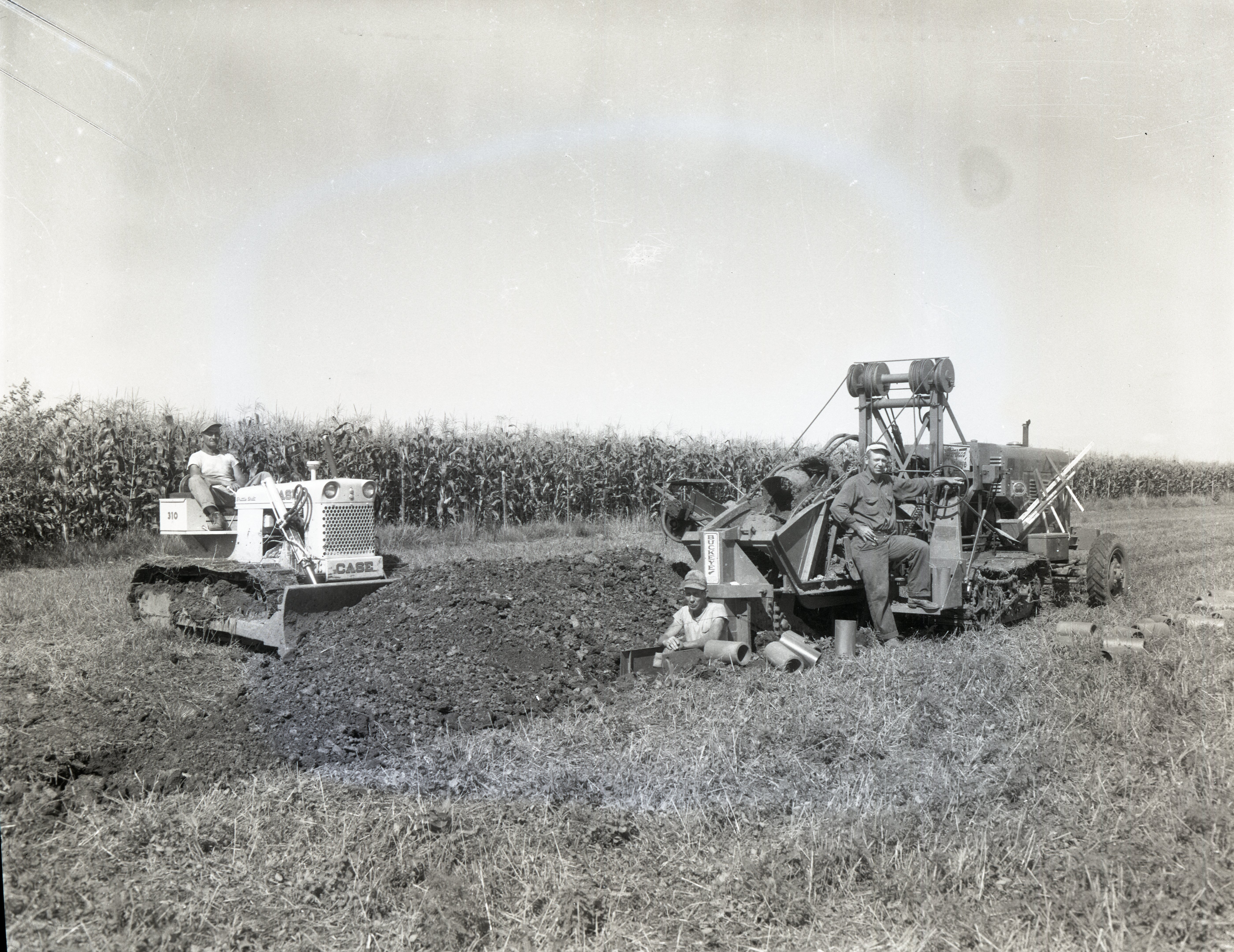 Two men in field with bulldozer and scraper