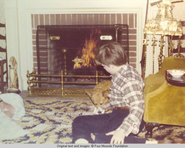 John, Jr. and corgy playing cards in front of fire place