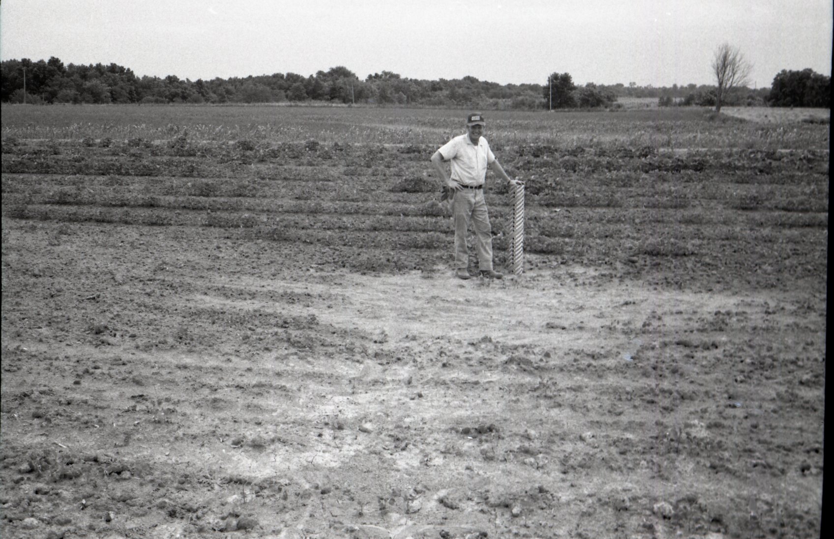 Man stands next to pipe in field
