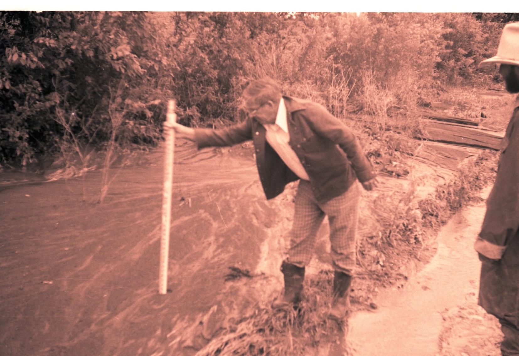 Man Measures Depth of Water in Flooded Area