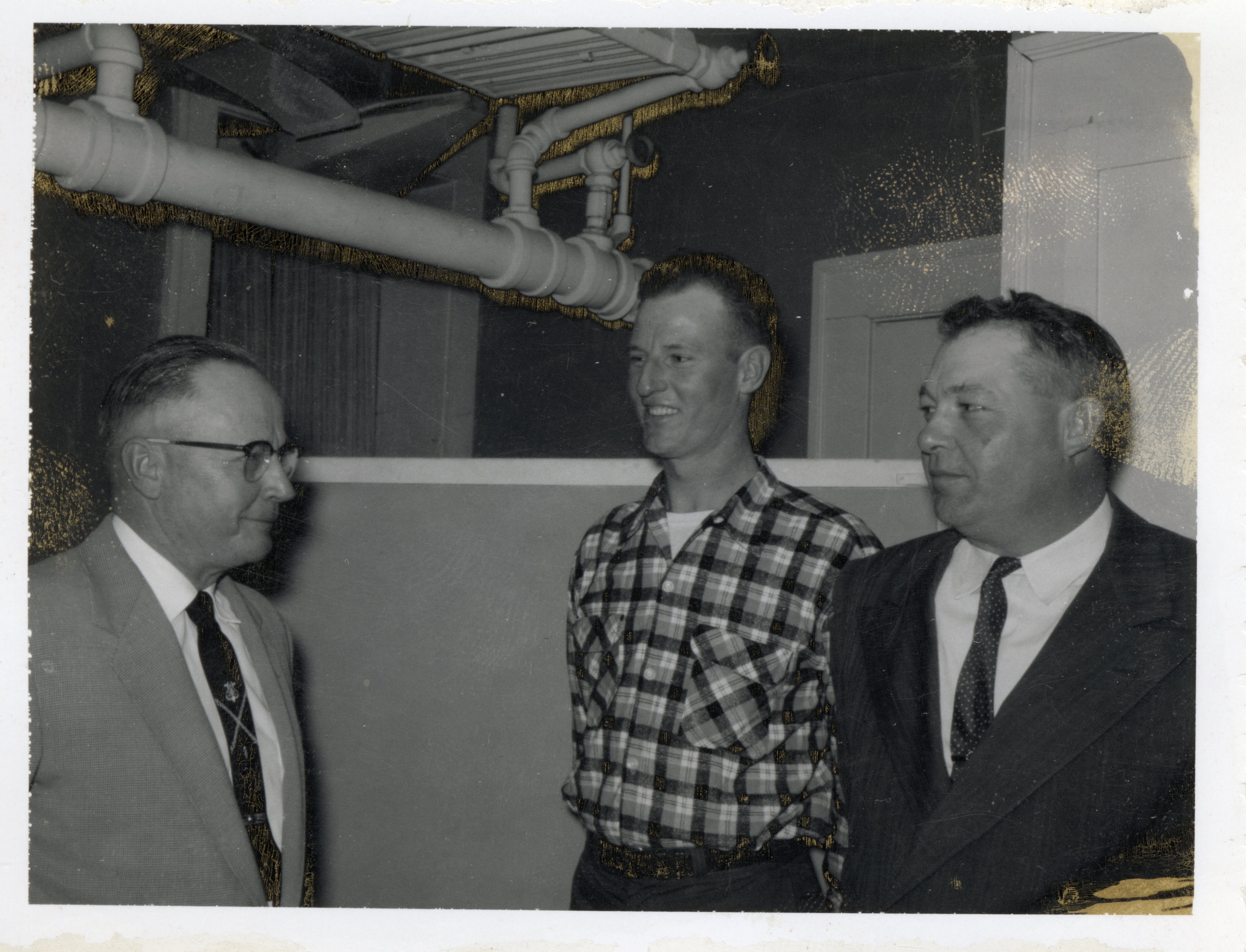 Three Unidentified Men Stand Facing Each Other with Pipes Overhead