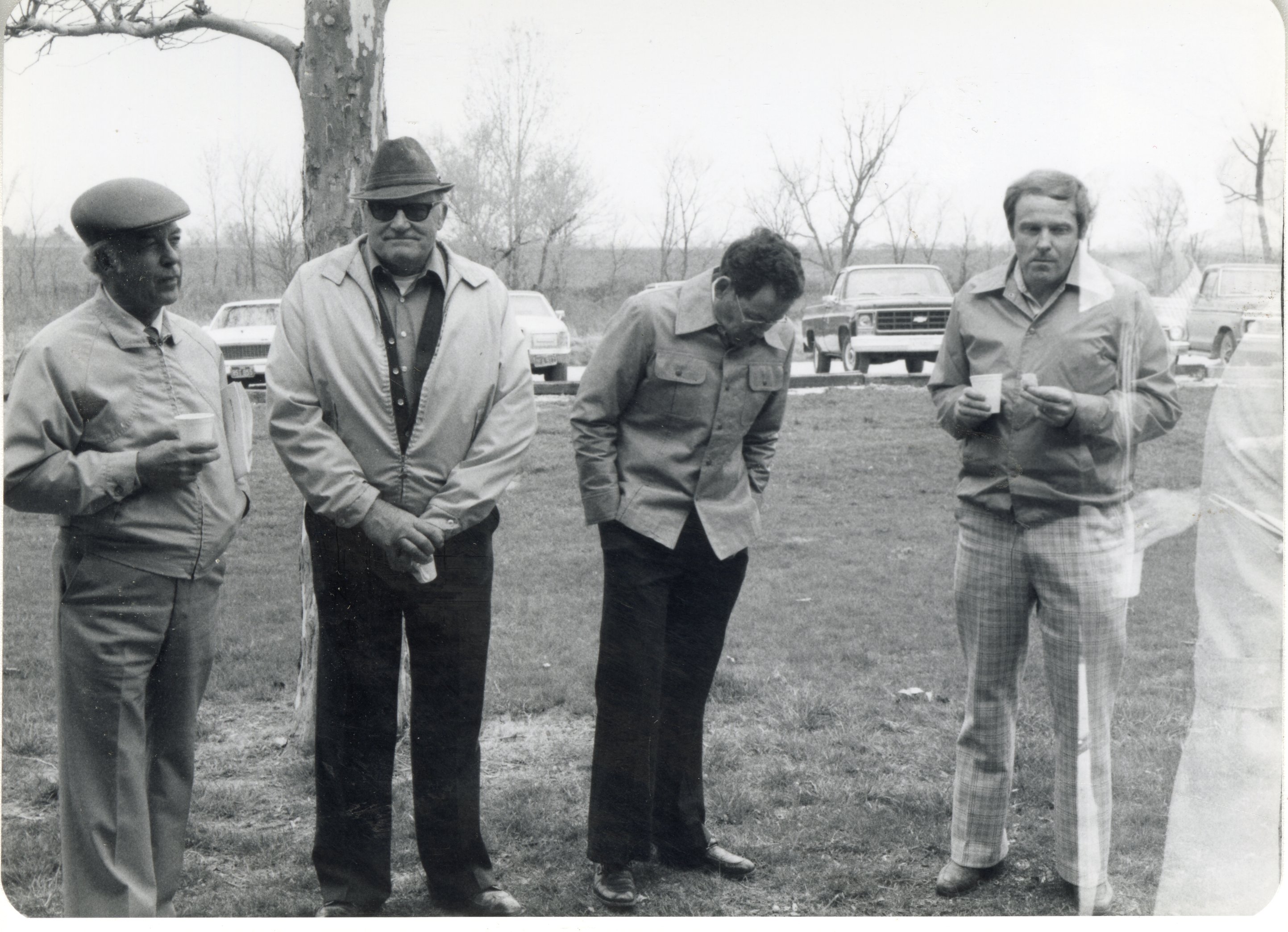 Men stand under tree during a meeting