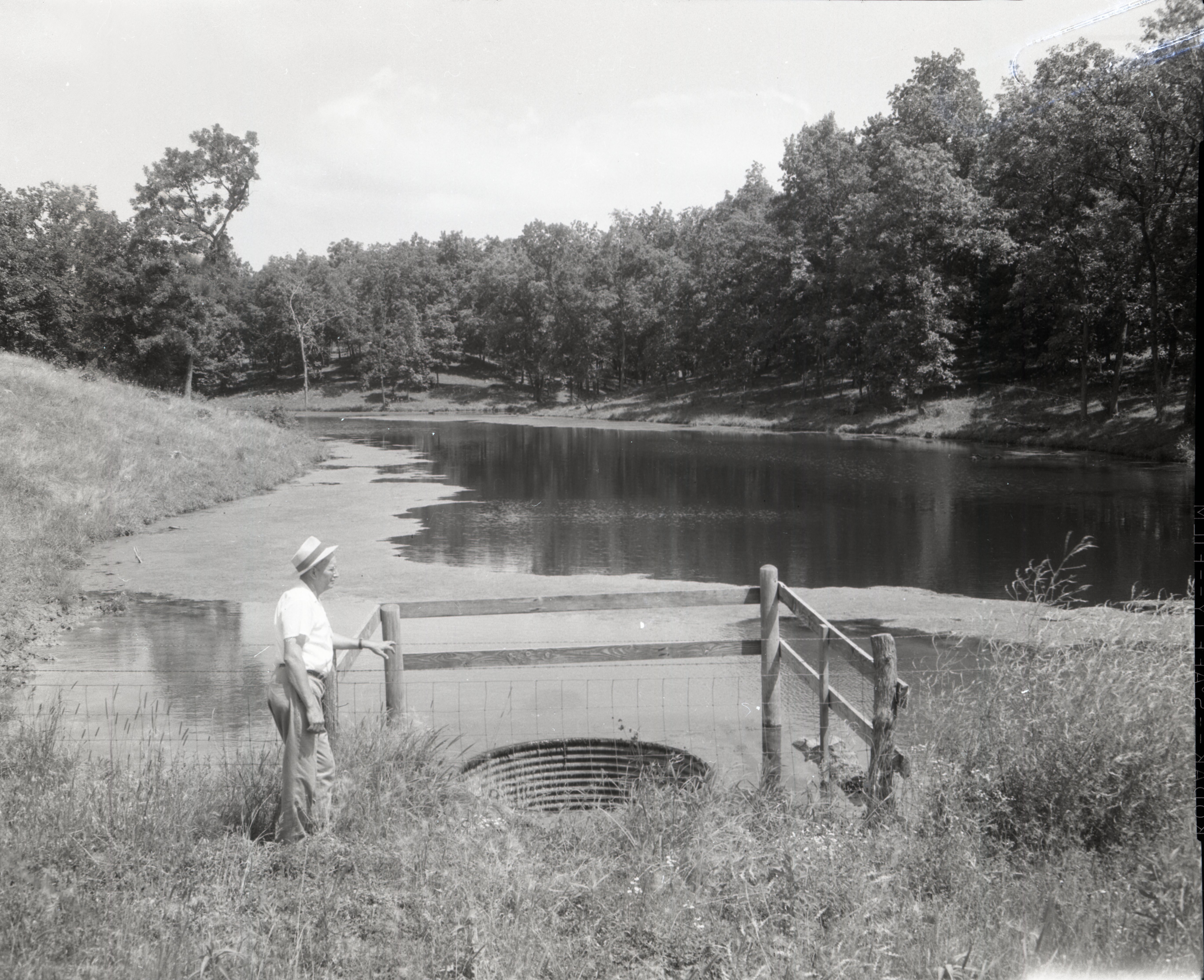 Man stands by drainage pipe by pond