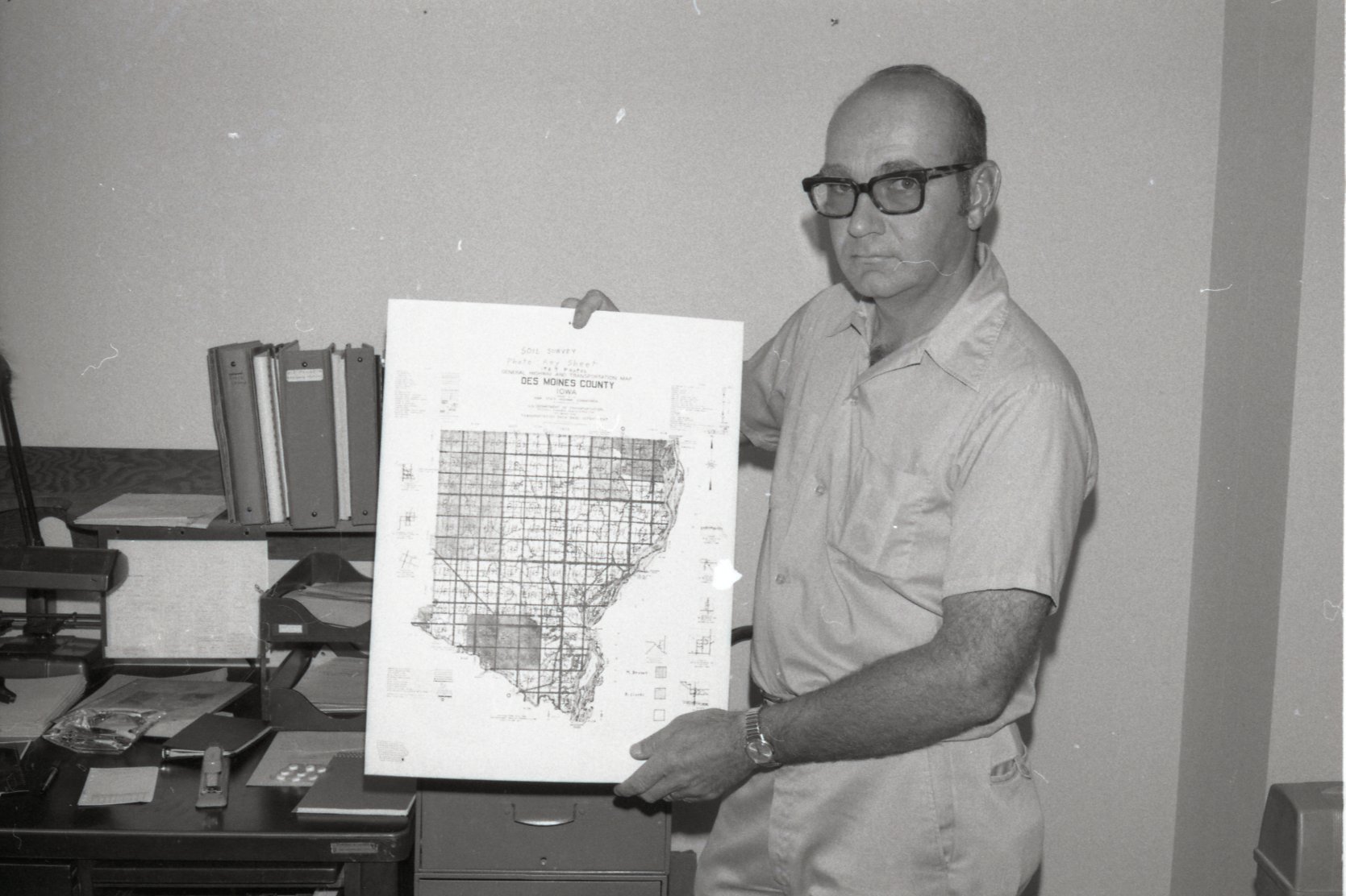 1975 Soil scientist Mel Brown man holds county oil survey map