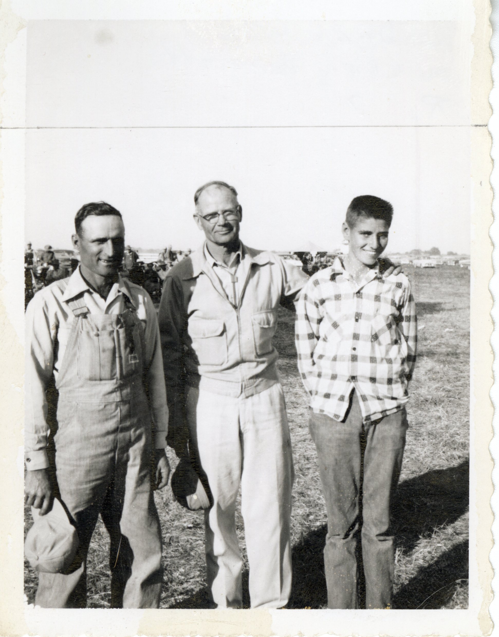 Three Men in Field Smile at Camera