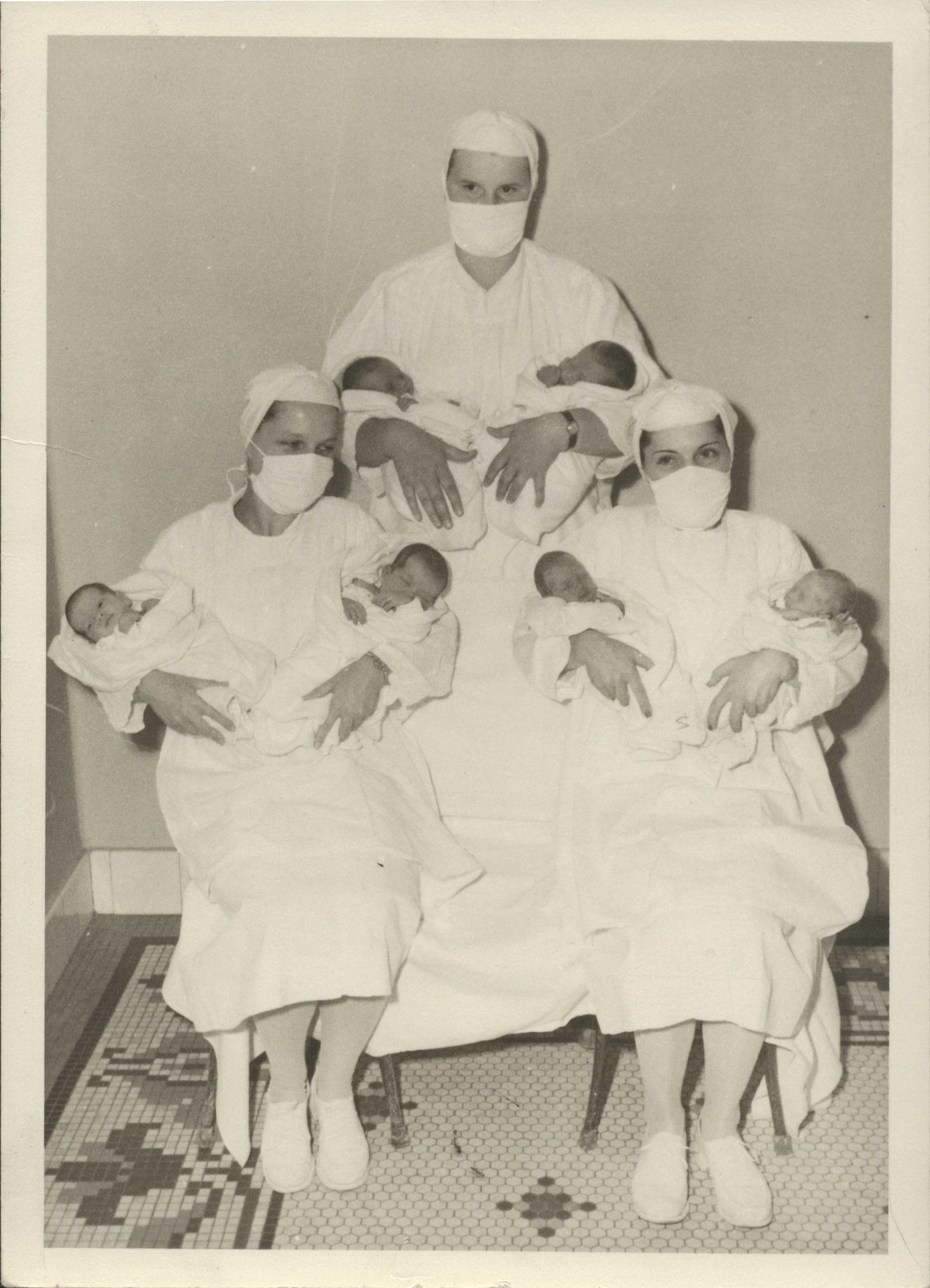 Nurses pose with newborns.