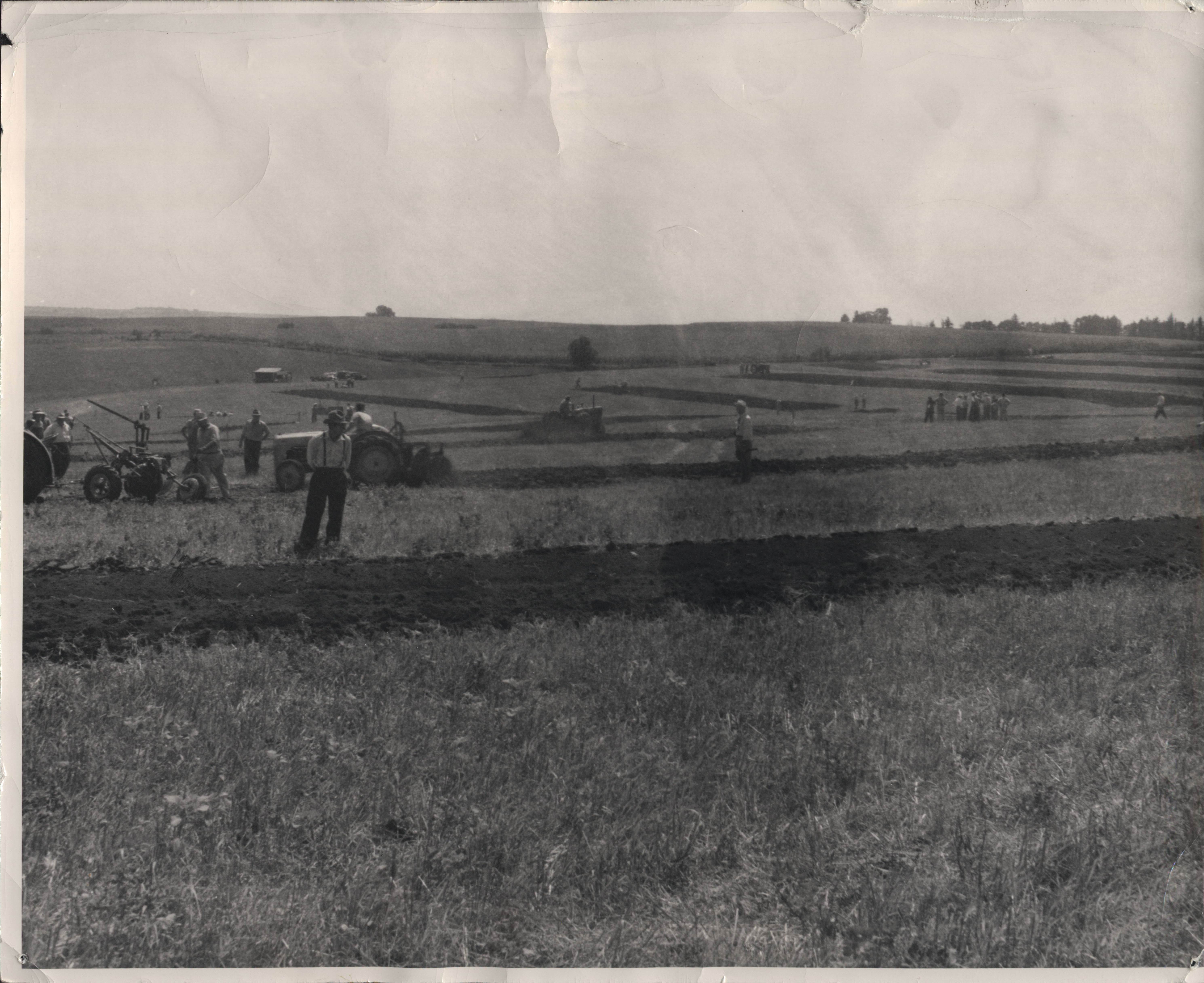 Men in field looking at strips of land that have just been plowed