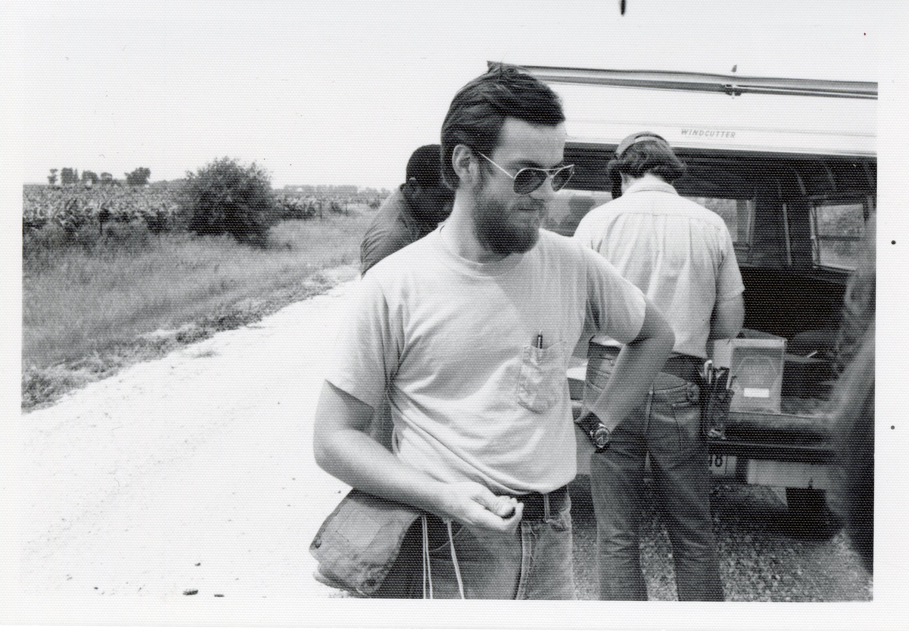 Three men stand in back of a van parked by a rural road