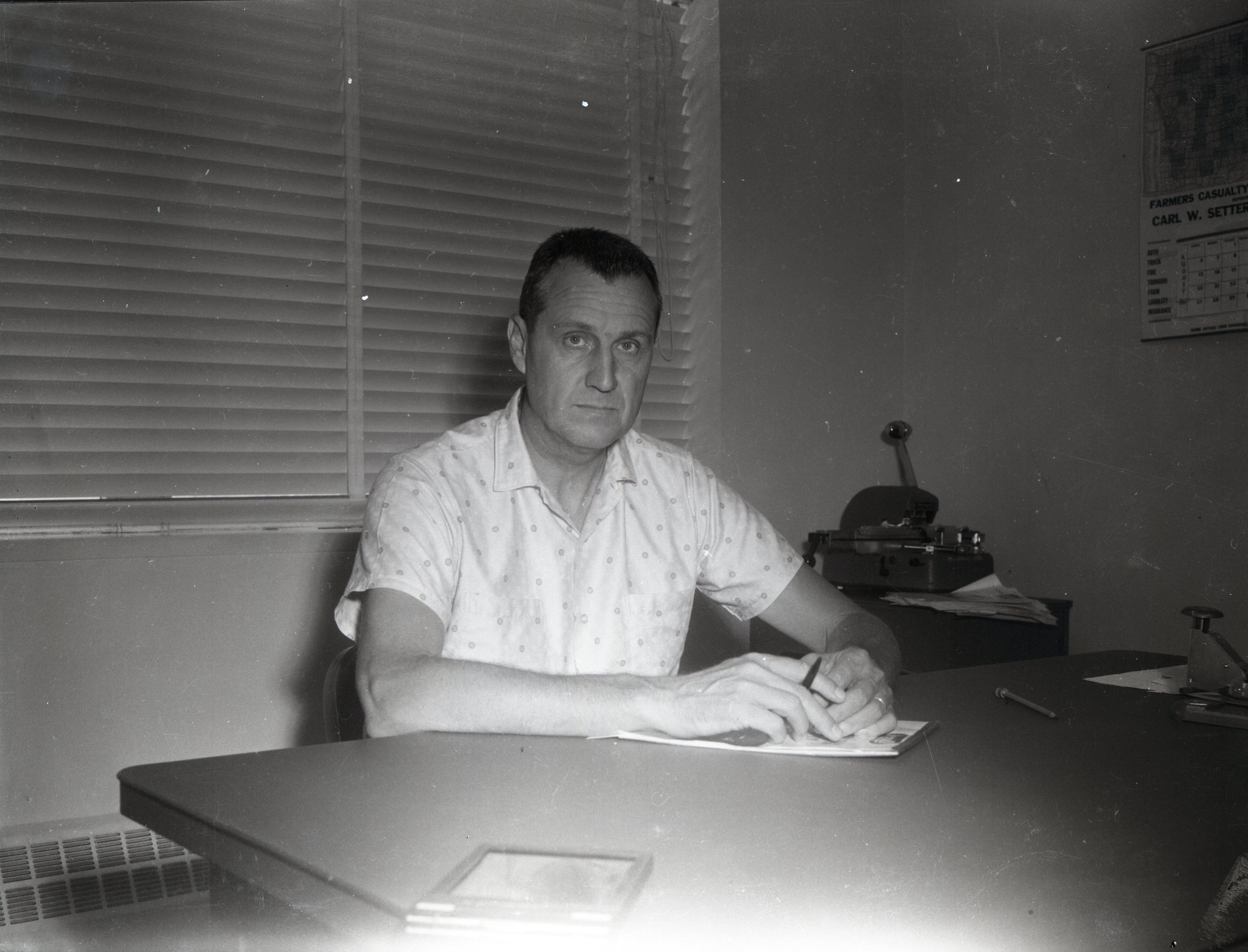 Unidentified man sits at desk holding pen