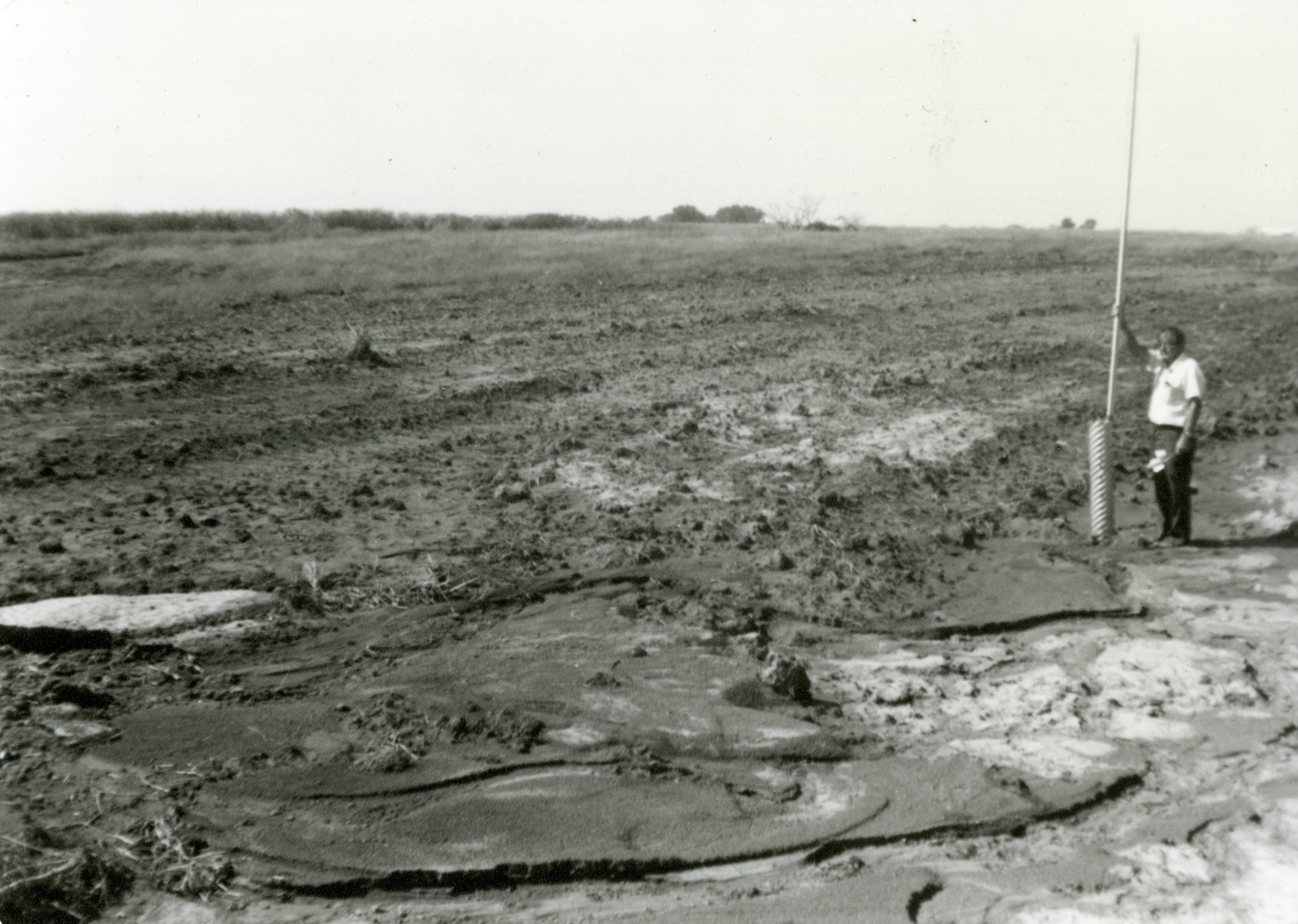 Man Stands by TOT Pipe in Field