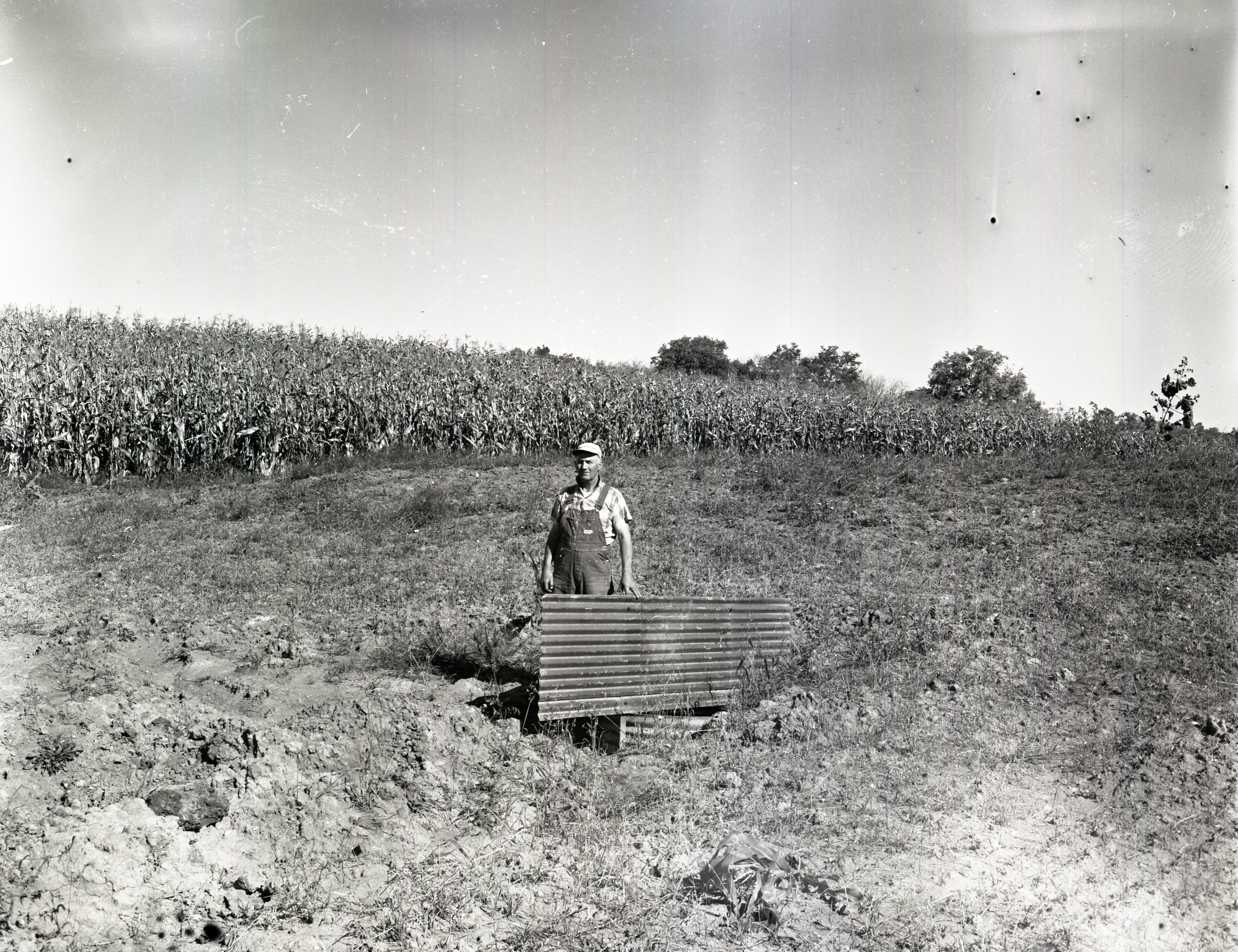 Farmer in overalls holds metal sheet in a field