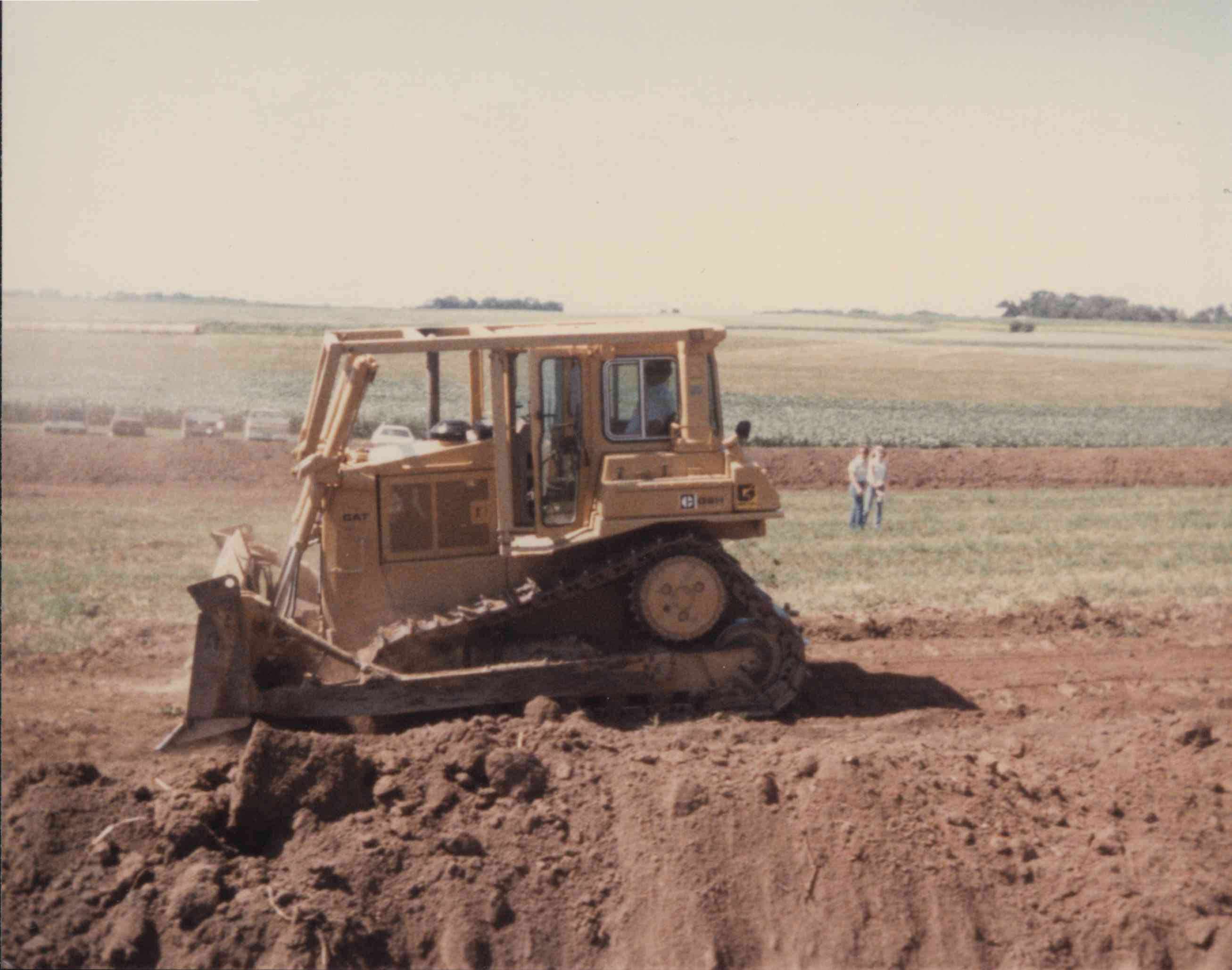 Couple Watching Bulldozer in Field