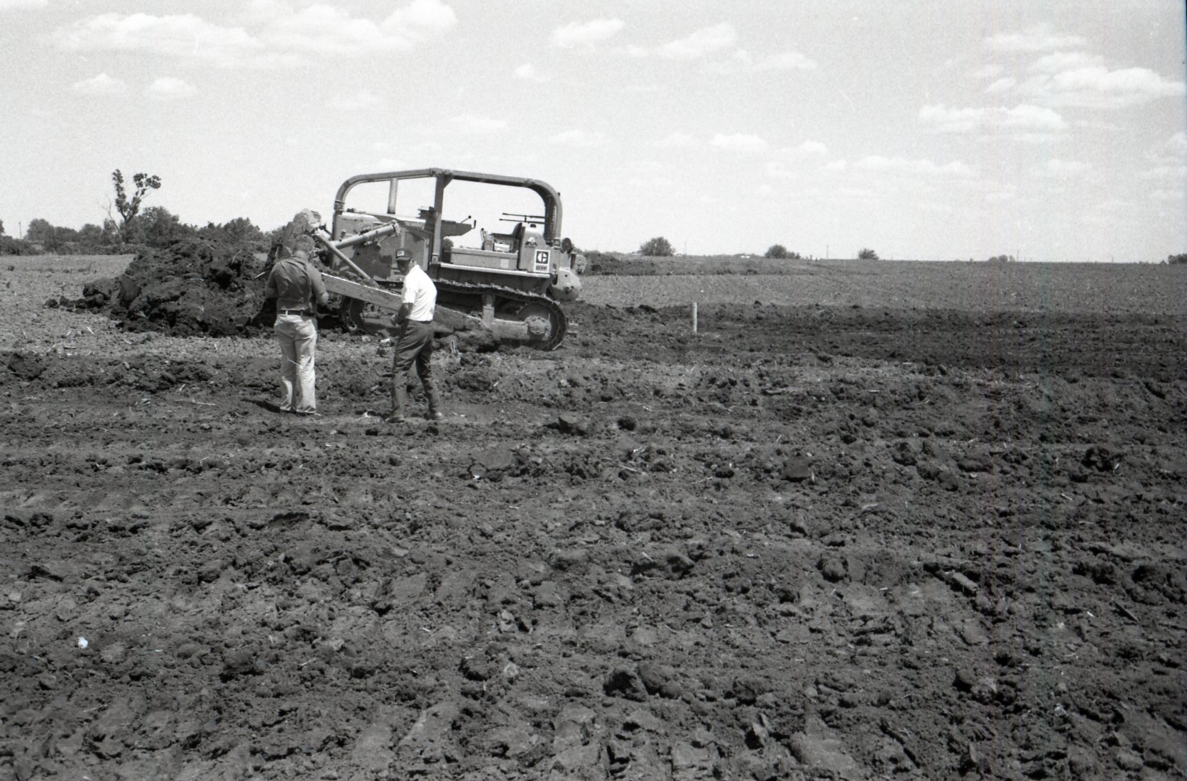 Two men stand in front of earthmoving machine