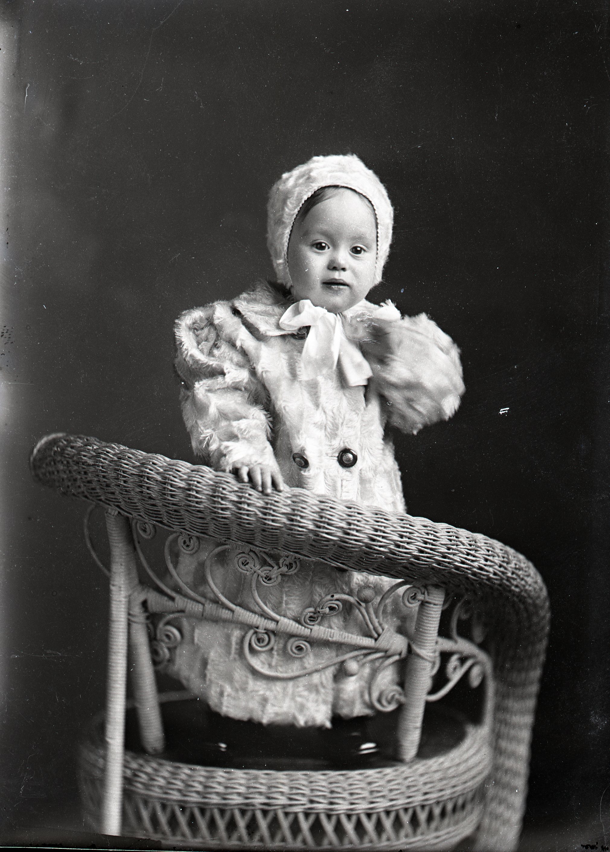 Toddler in fur coat on chair