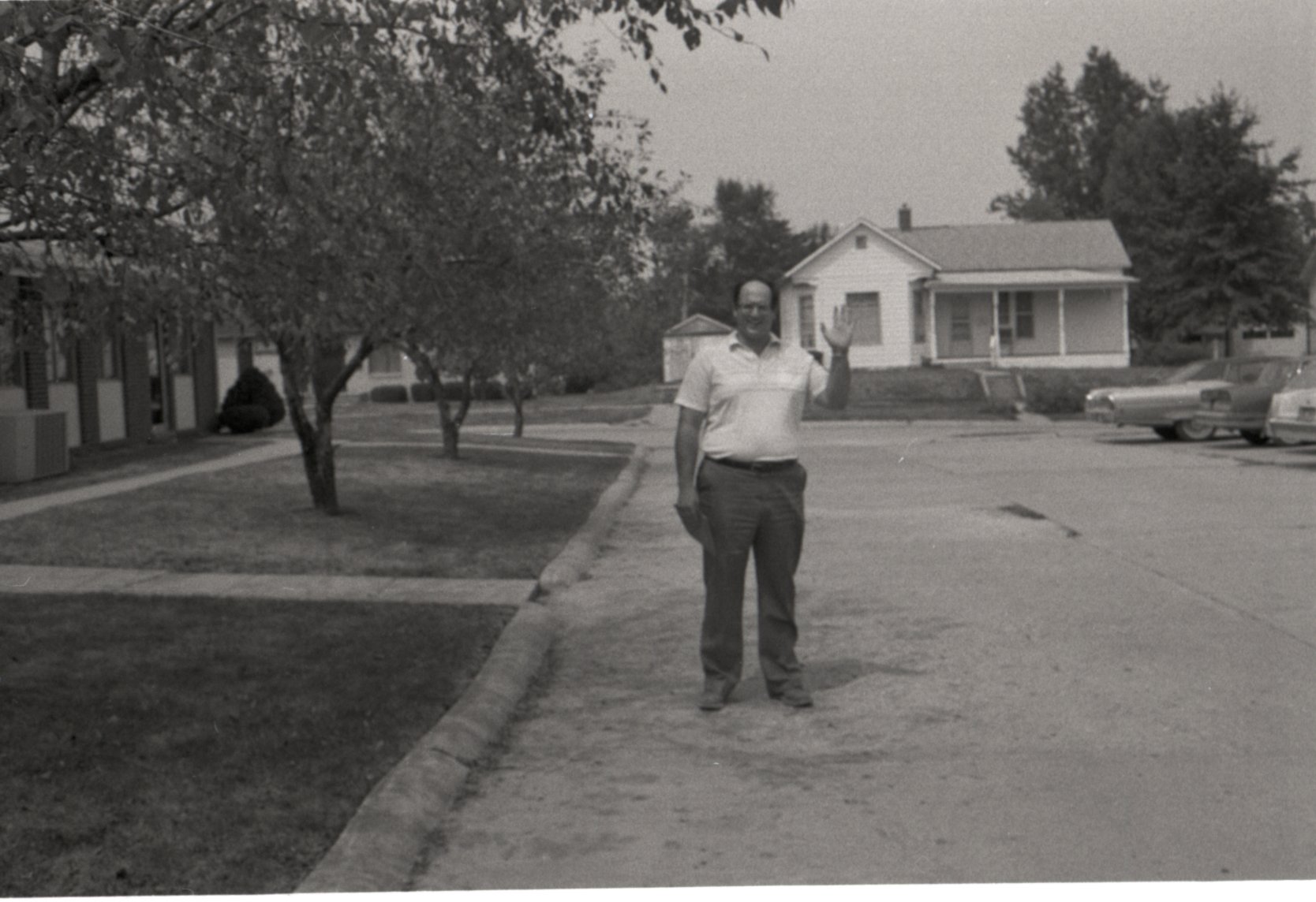 Unidentified Man Stands in Street with Hand Raised