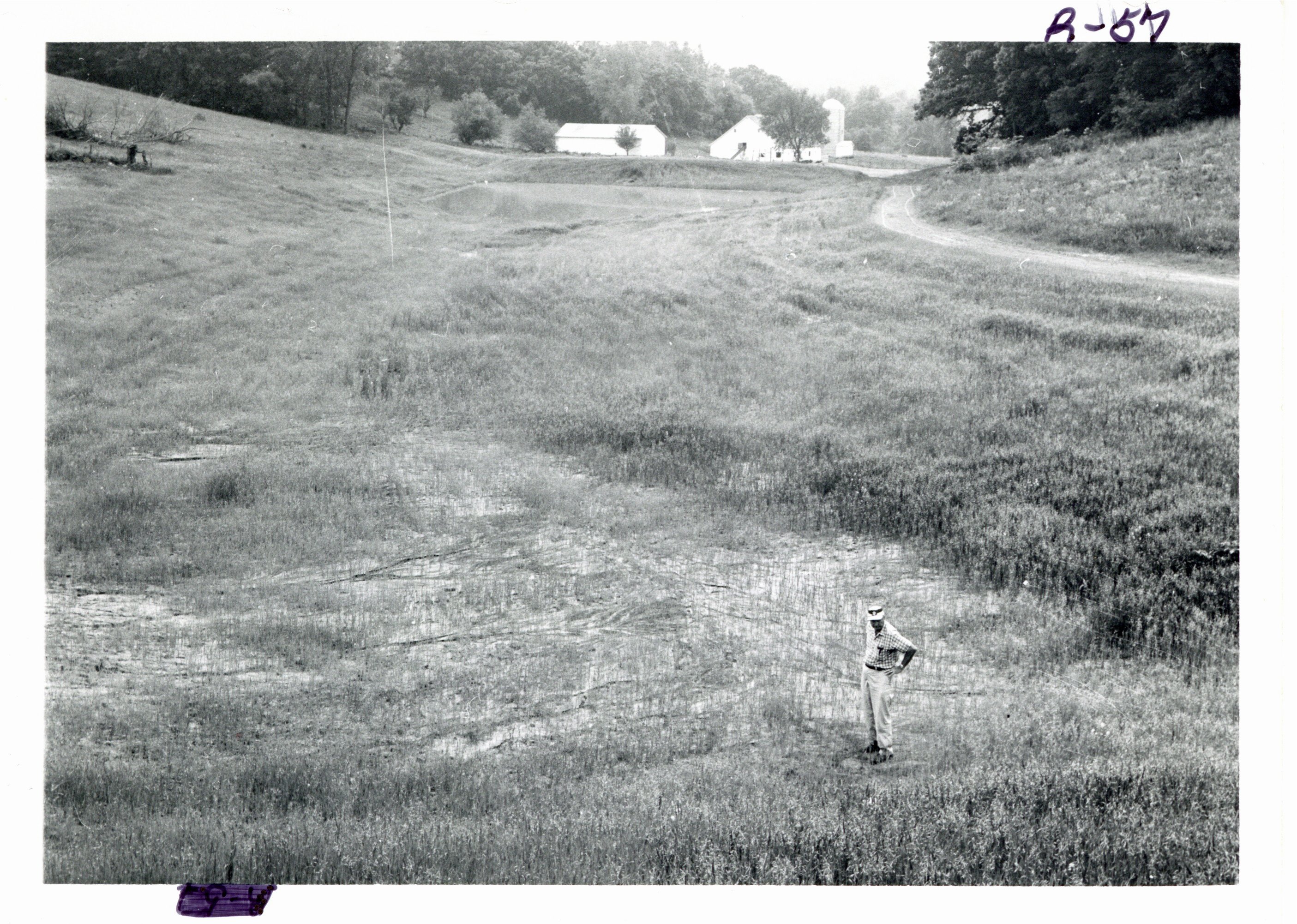 Harold Shold standing below upper structure of outlet pipe, 1967