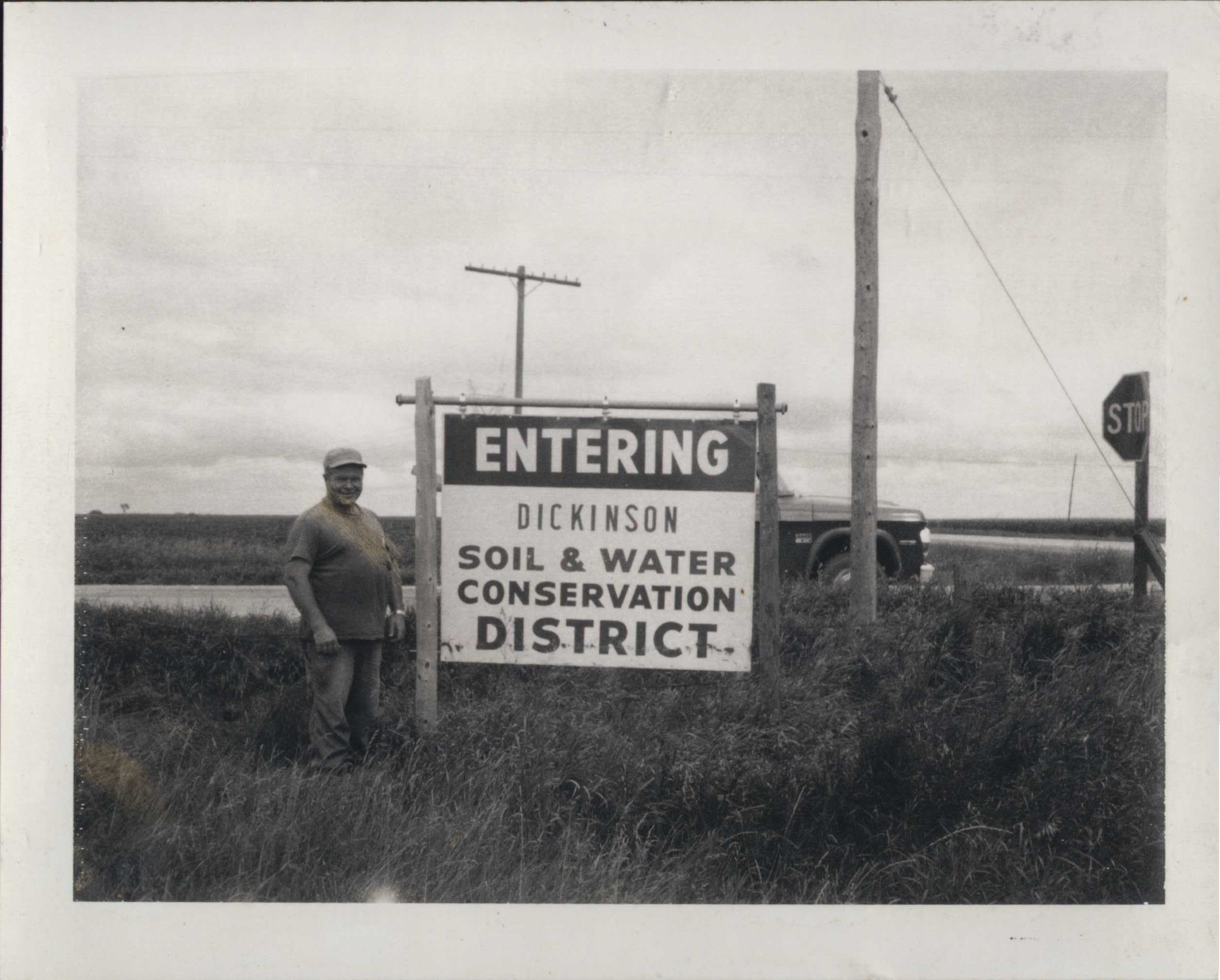 Man Standing by the 'Entering Dickinson Soil & Water Conservation District' Sign.
