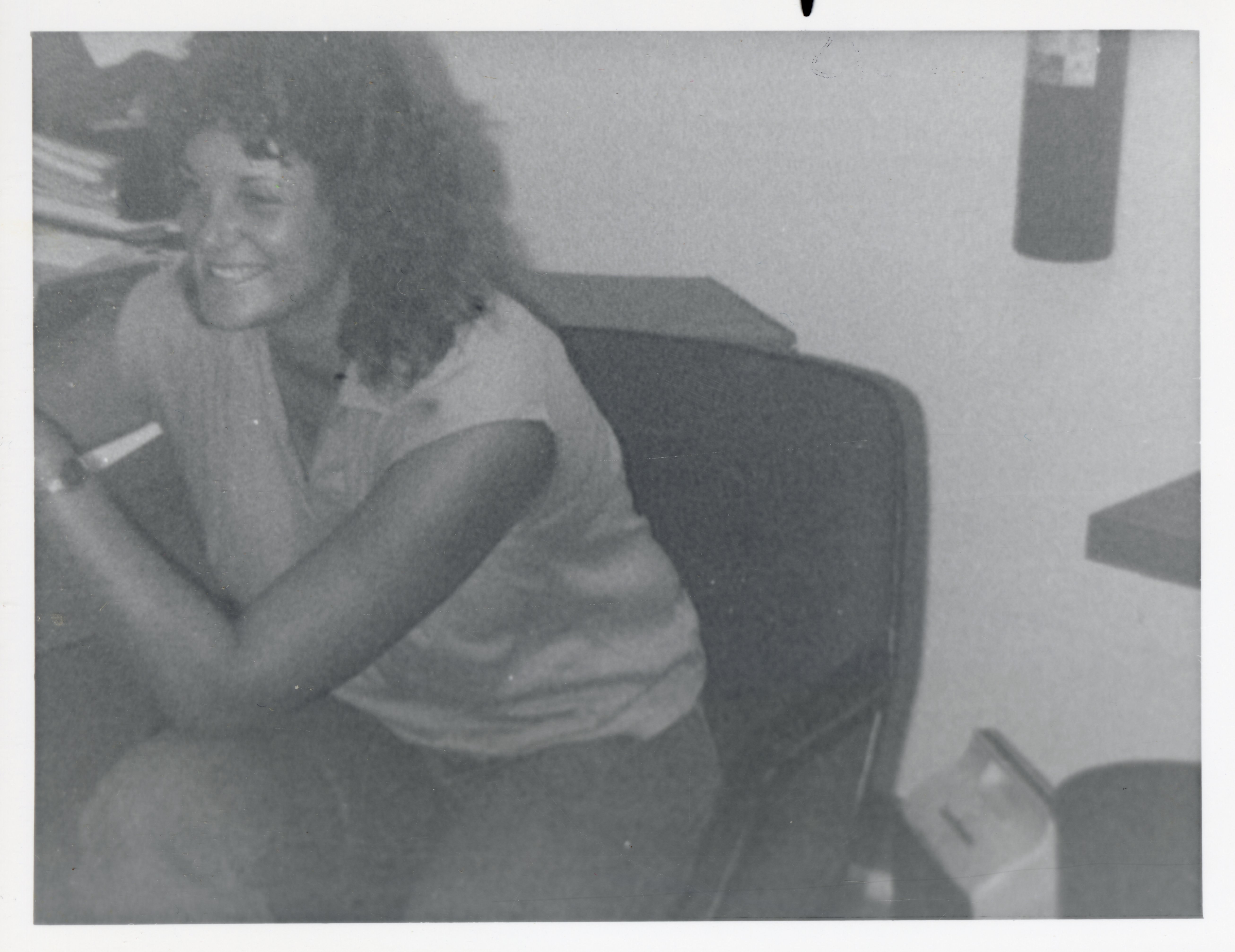 Unidentified Smiling Woman with Curly Hair Sits in Chair