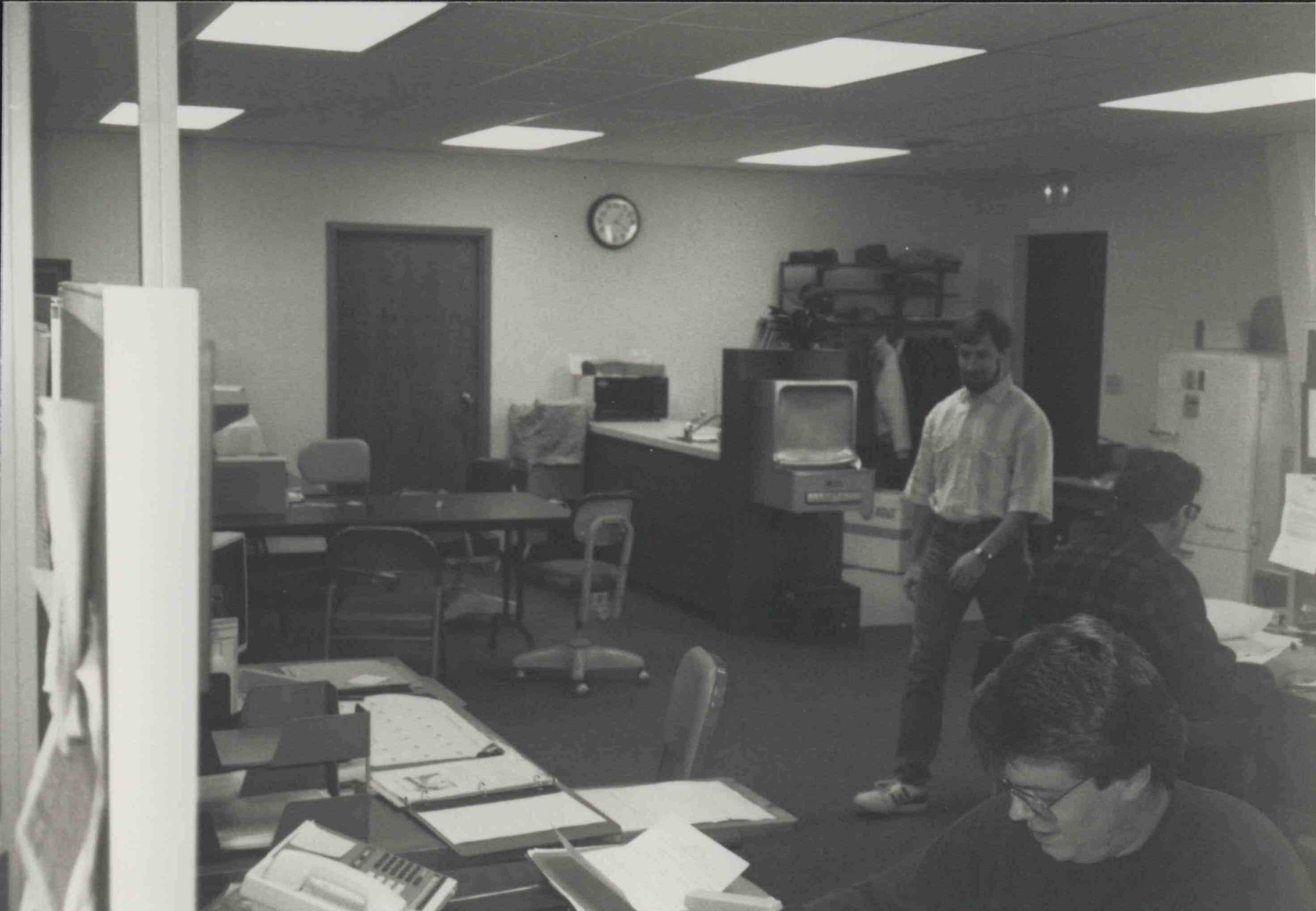 Office photo of man walking and two sitting