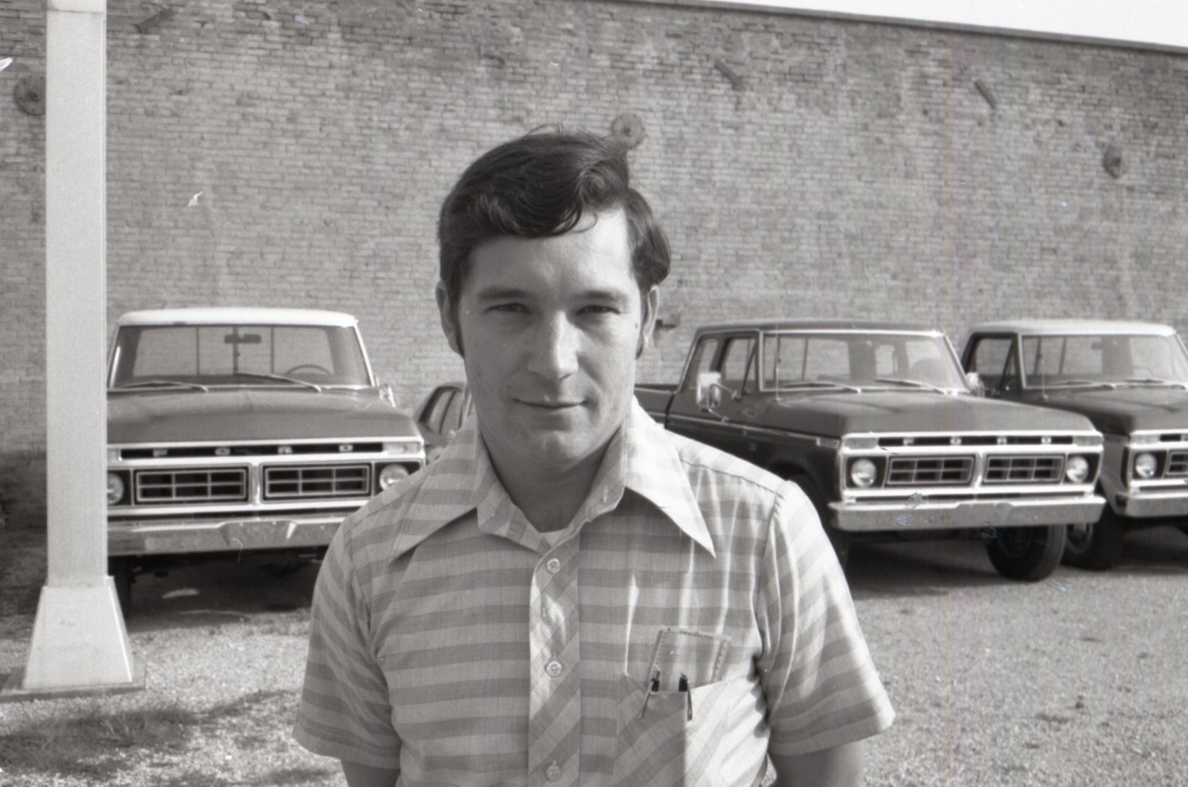 Unidentified man stands in front of trucks