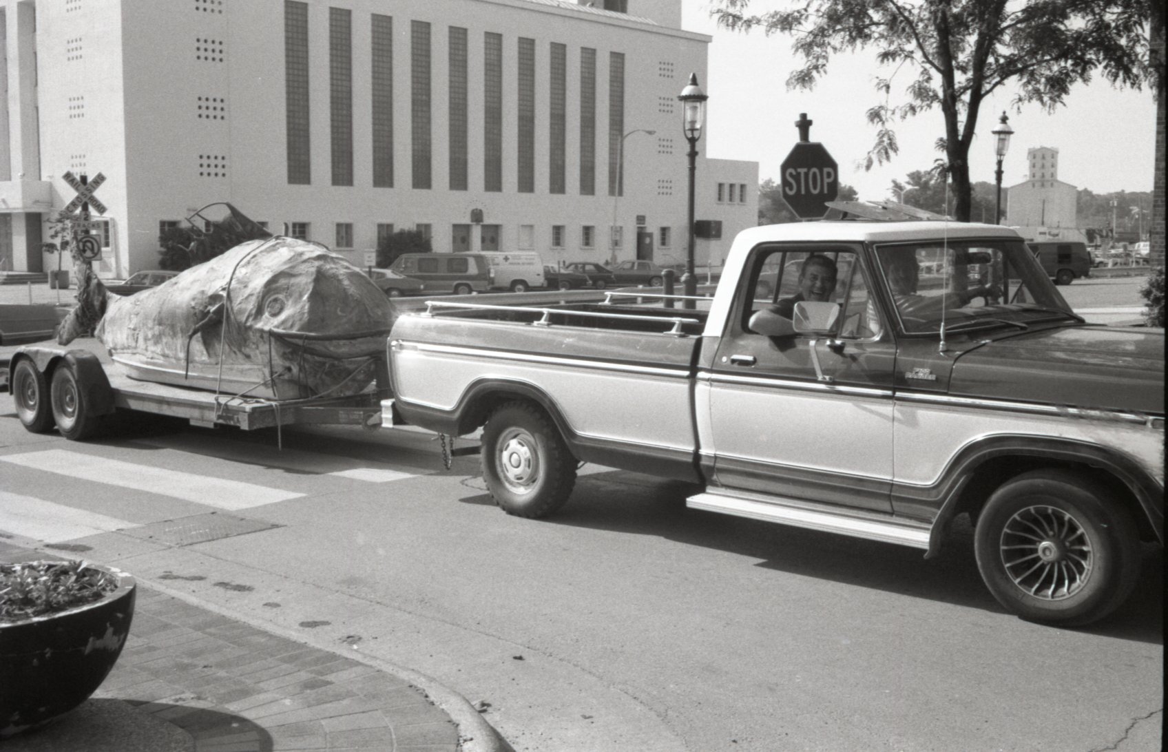Truck pulling trailer with two smiling men inside