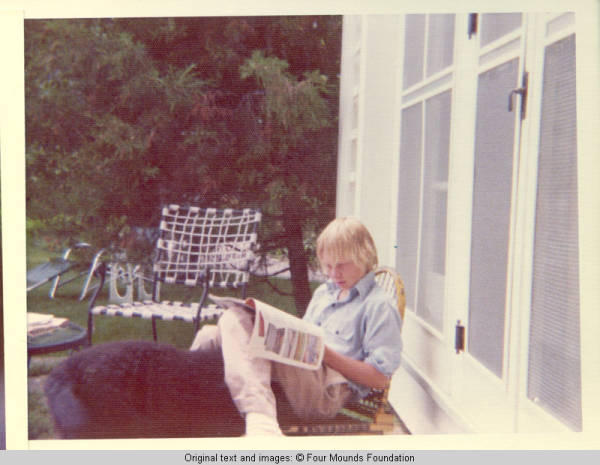 Jim reading magazine with Sadie, the dog outside Sun porch 