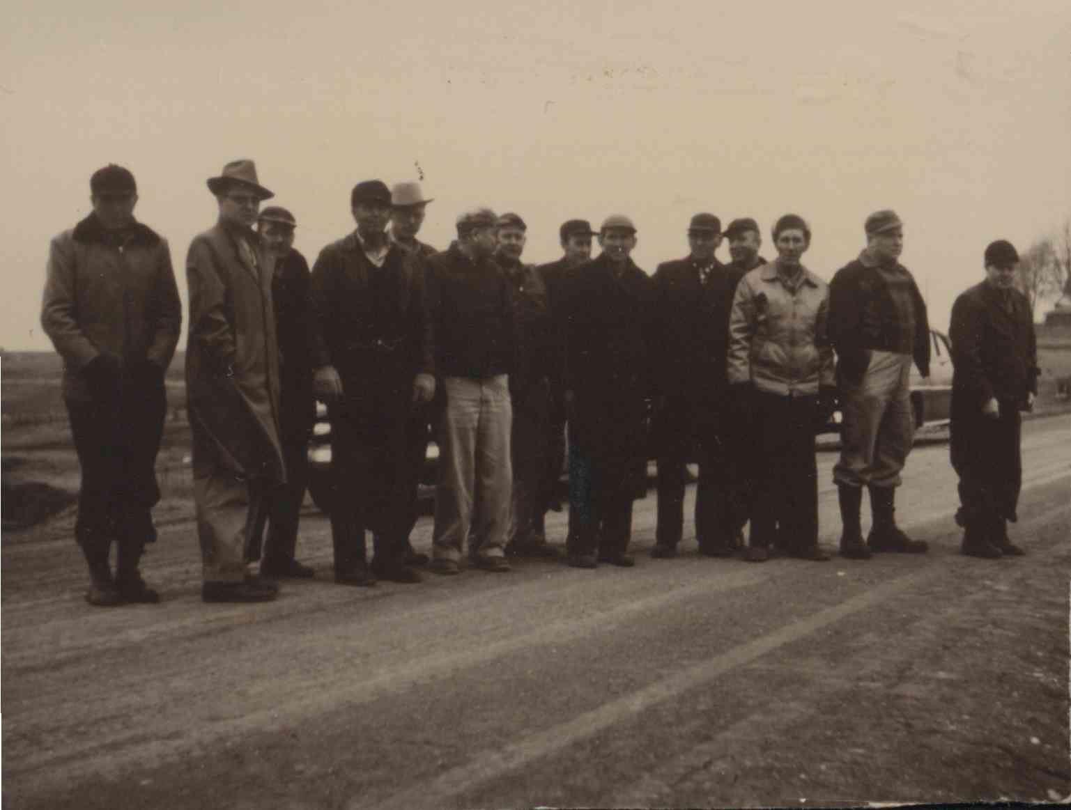 Unidentified gathering of people standing on an unpaved road