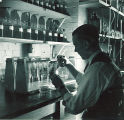 Man working with vials and chemistry equipment, The University of Iowa, 1930s